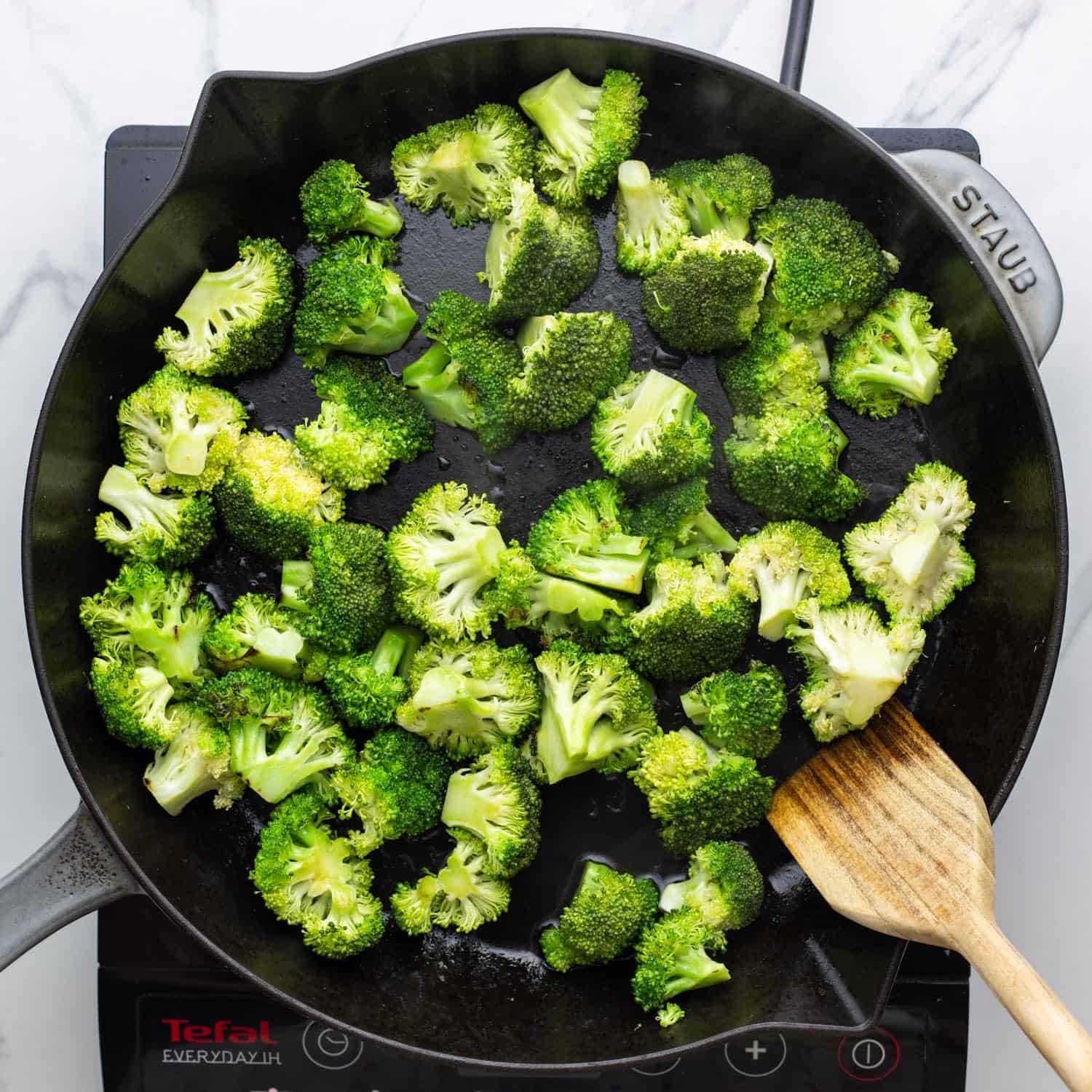 broccoli florets stir fried in a large cast iron skillet.