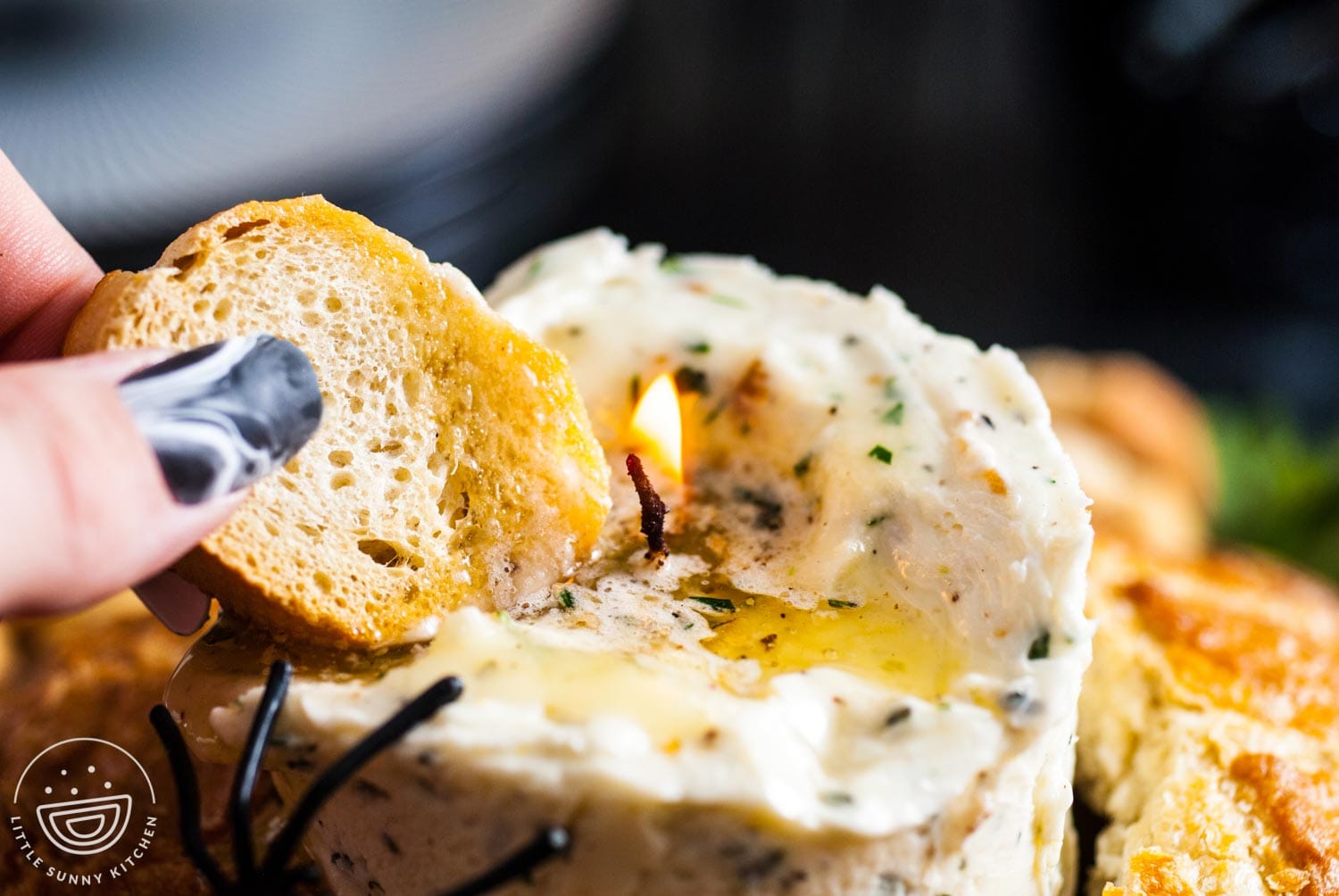 a hand dipping a slice of bread into a lit butter candle.