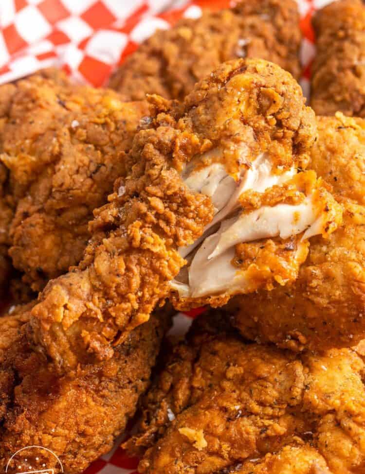 Crispy fried chicken drumstick showing the white meat on the inside to show doneness