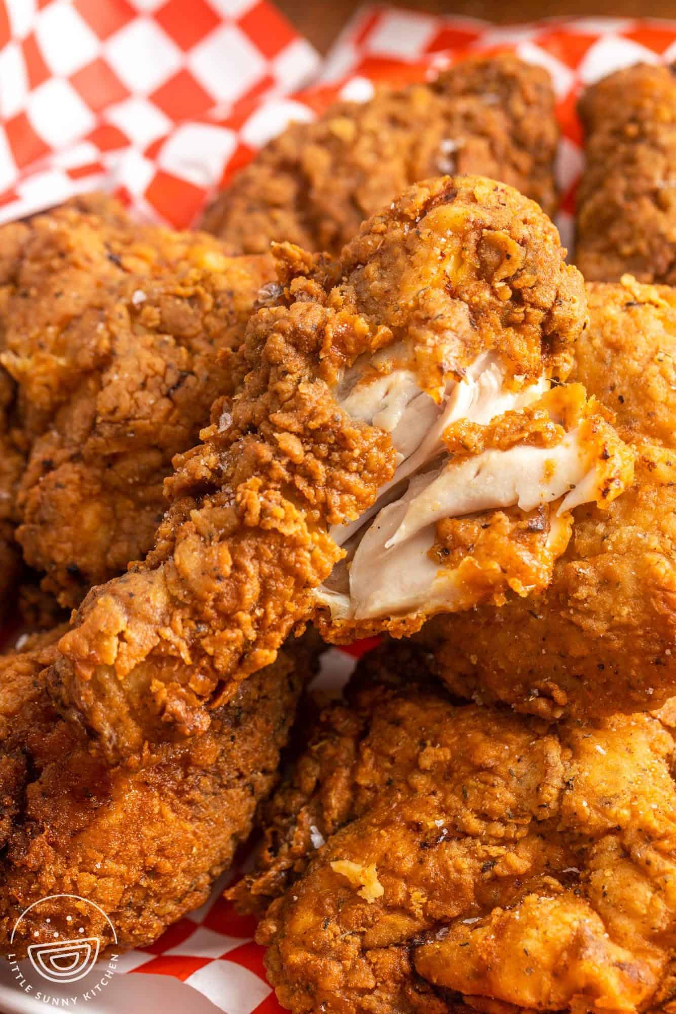 Crispy fried chicken drumstick showing the white meat on the inside to show doneness