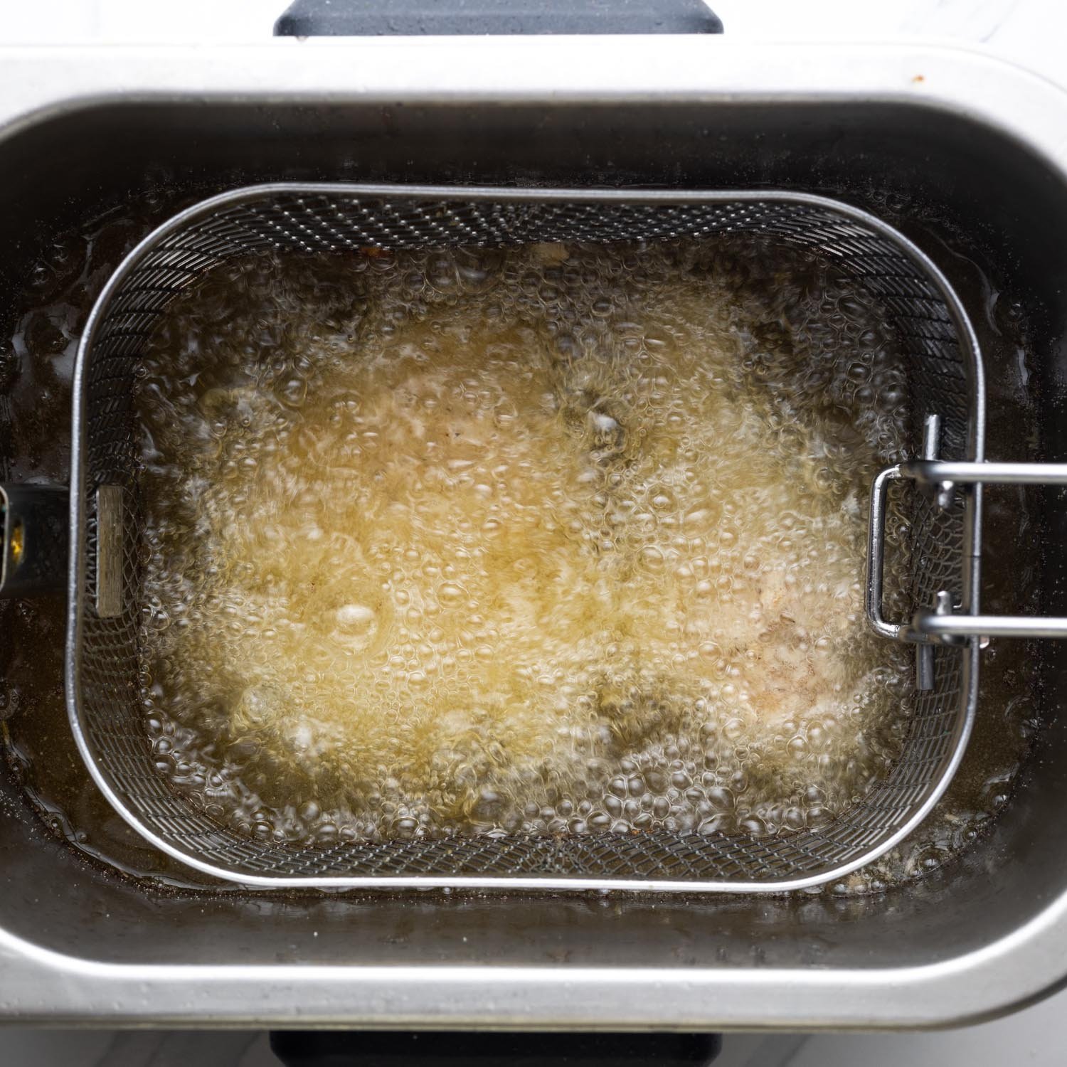 Chicken being fried in a fryer