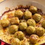 cooked browned chicken pesto meatballs in a pan with oil.