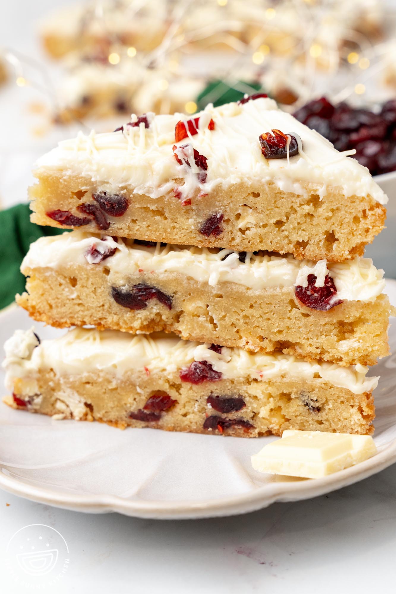 three triangle shaped cranberry bliss bars stacked on a white plate.