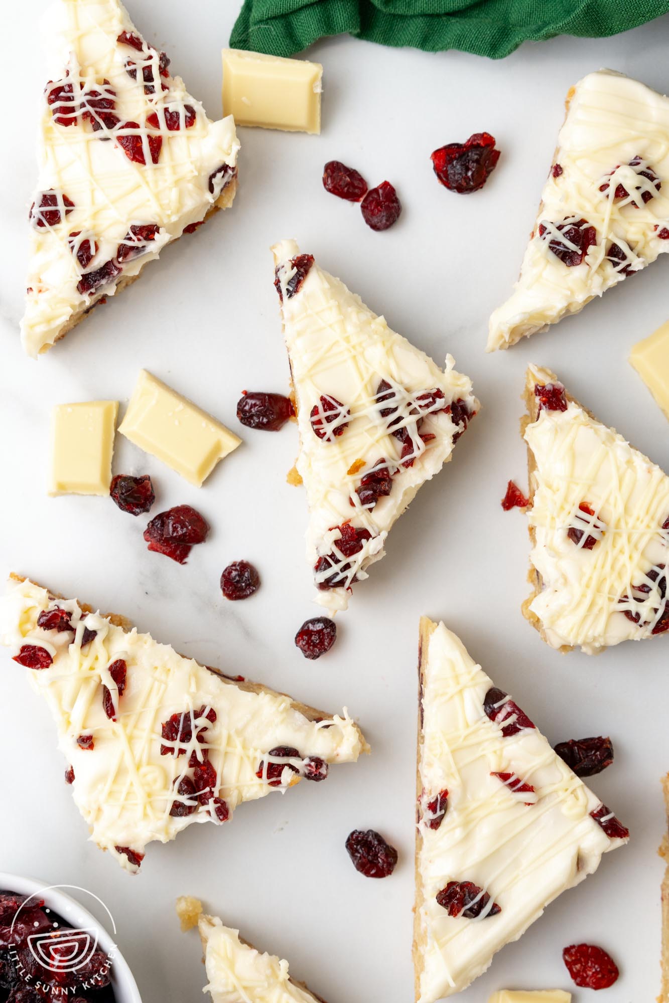 triangular cranberry bliss bars with frosting arranged on a counter.