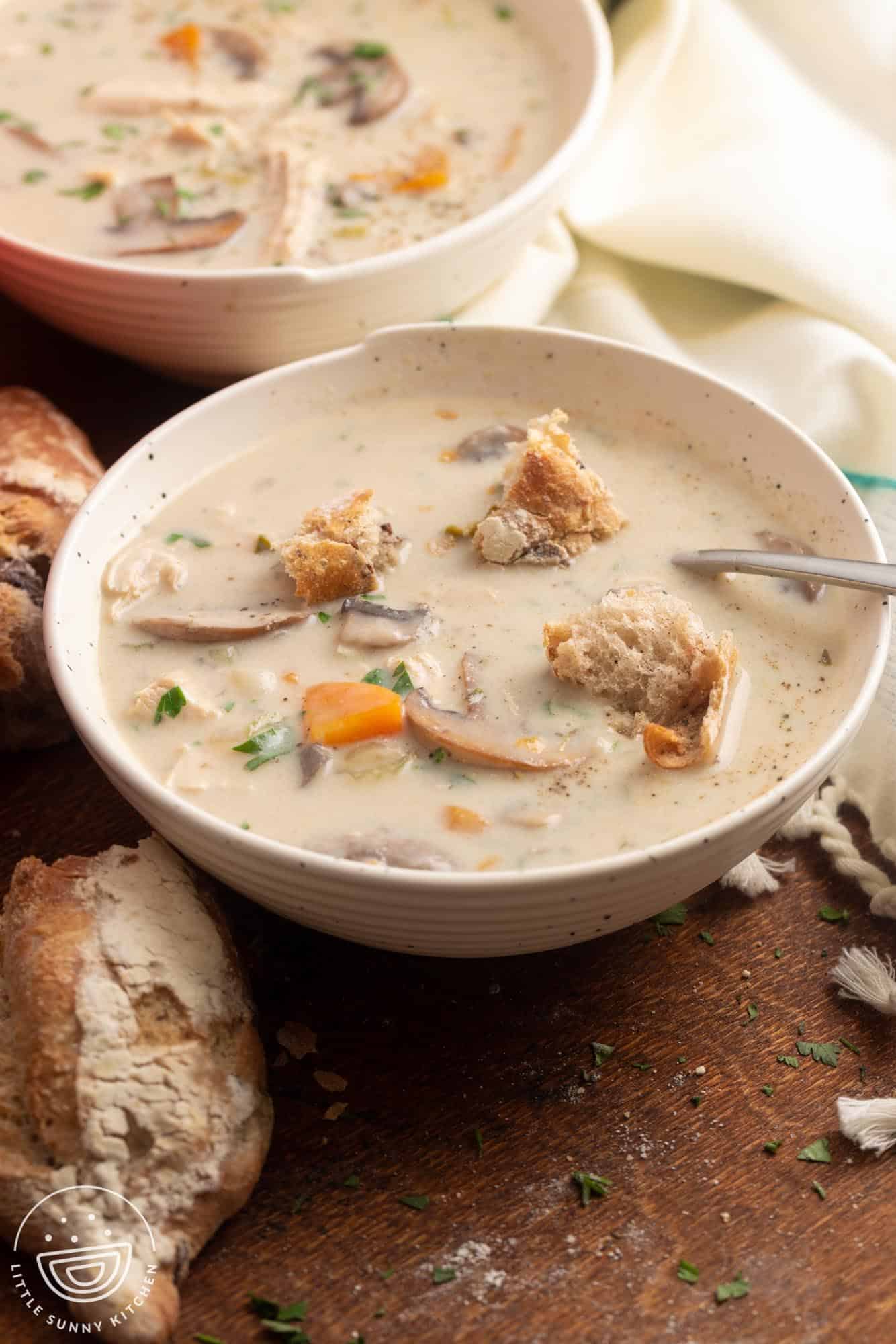 a bowl of creamy mushroom chicken soup with rustic bread croutons.