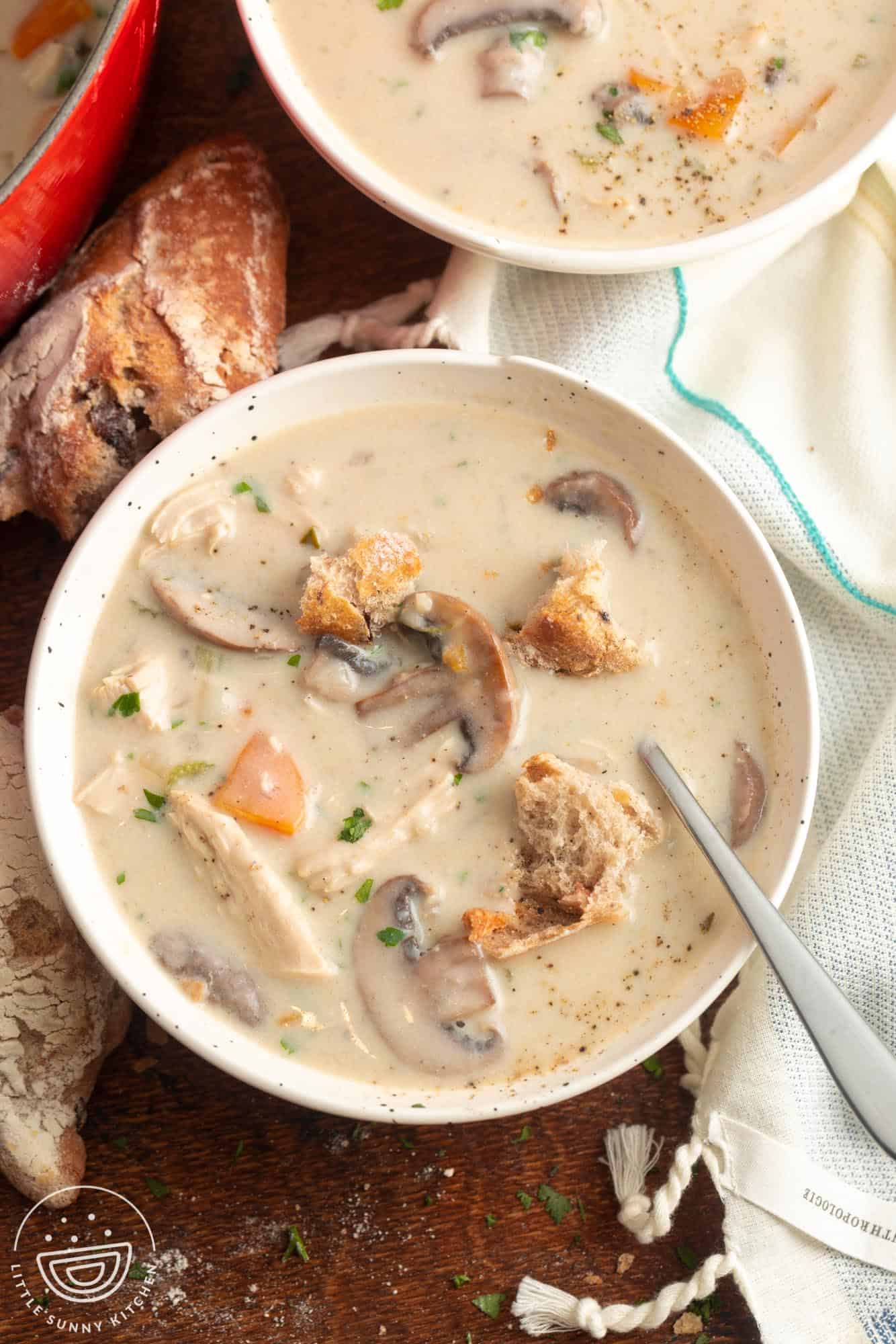 two bowls of creamy soup with chicken and mushrooms topped with croutons.