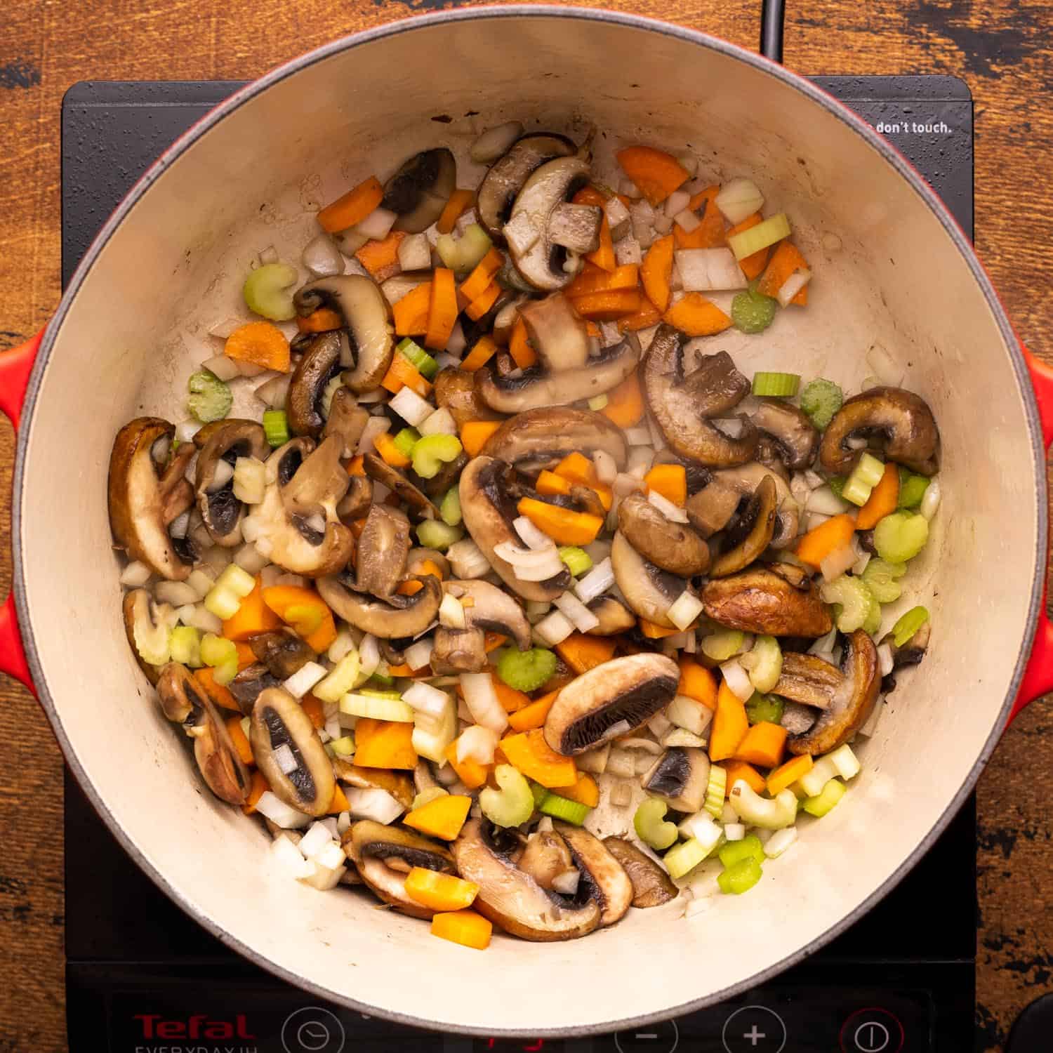 sauteed carrots, onions, and celery with sliced mushrooms in a dutch oven.