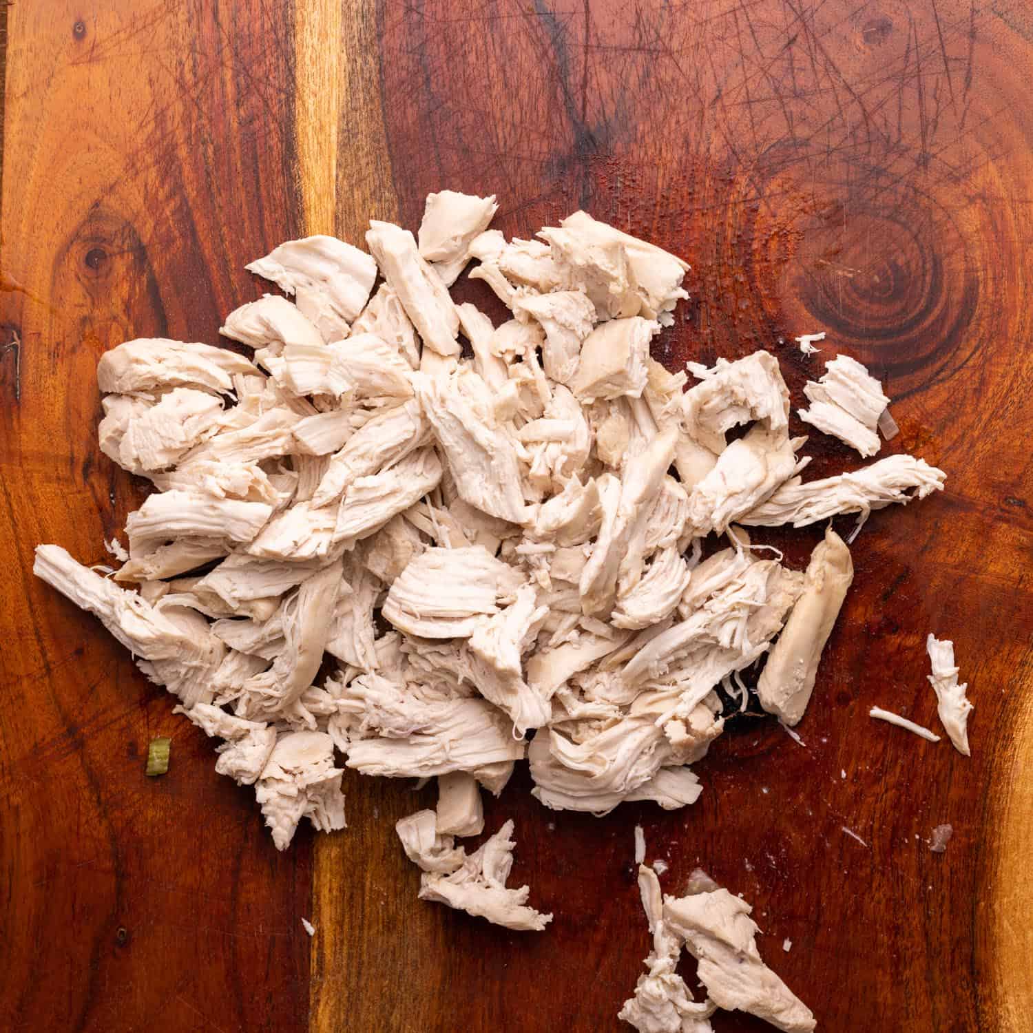 shredded chicken breast on a wood cutting board.