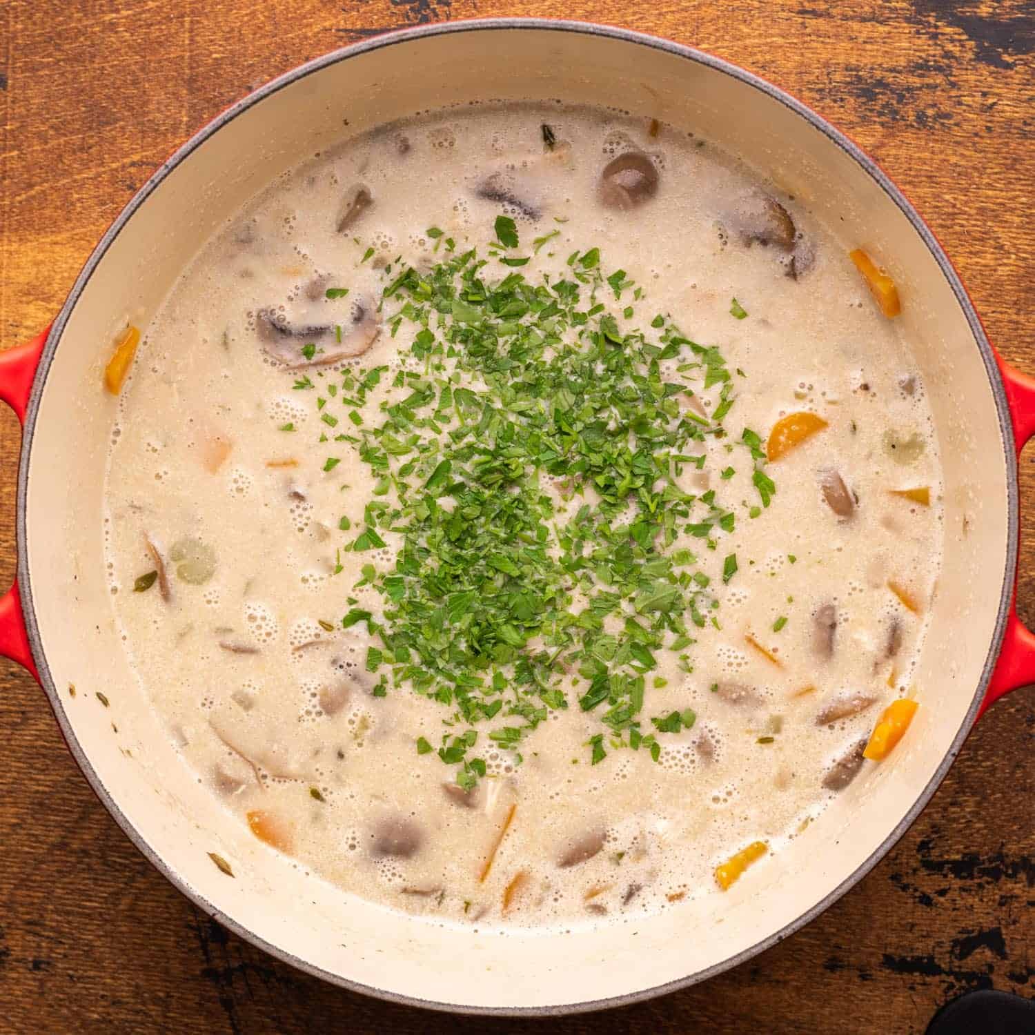 chopped parsley added to a pot of mushroom soup with chicken.