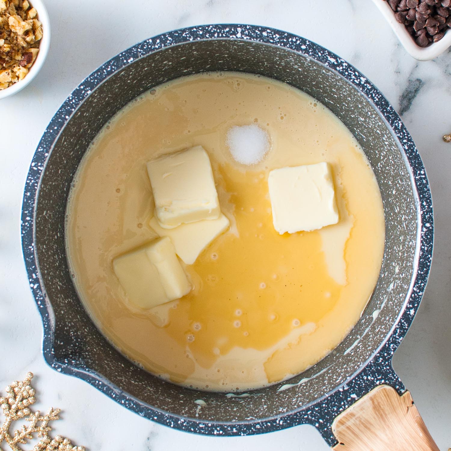 butter, sugar, and sweetened condensed milk cooking in a blue and white enameled pot.