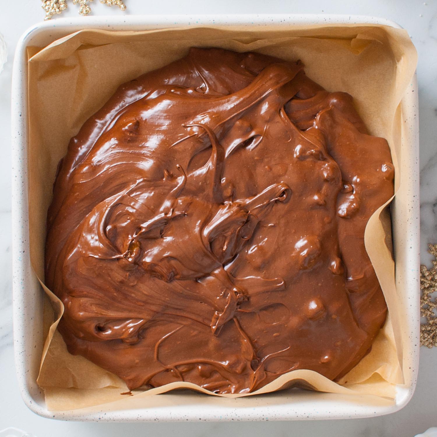 Fudge poured into a square pan lined with parchment paper.