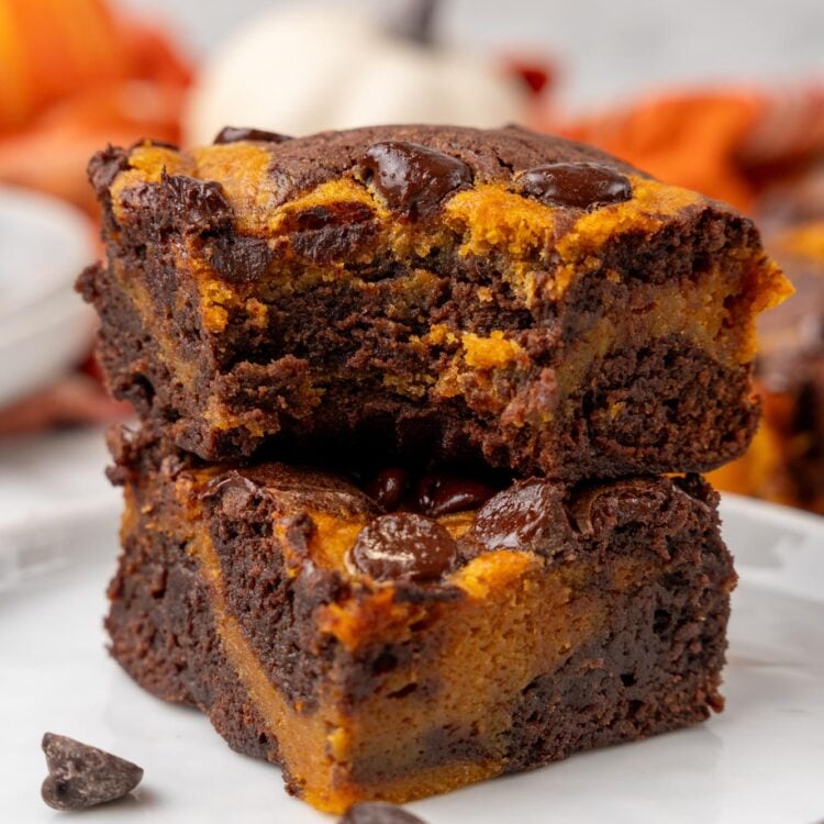 two pumpkin brownies in a stack. the top one has a bite taken to show the chewy texture.