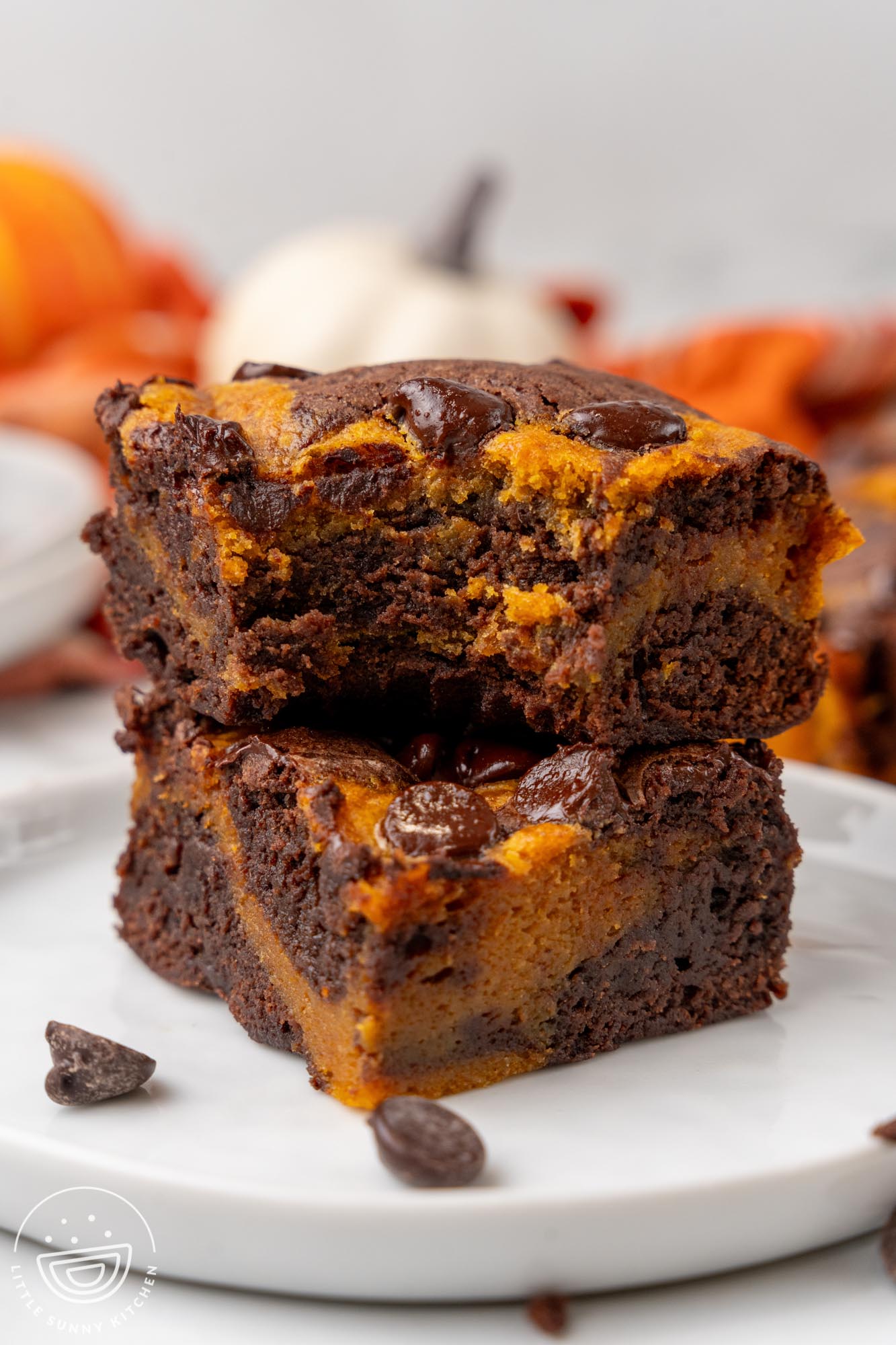 two pumpkin brownies in a stack. the top one has a bite taken to show the chewy texture.