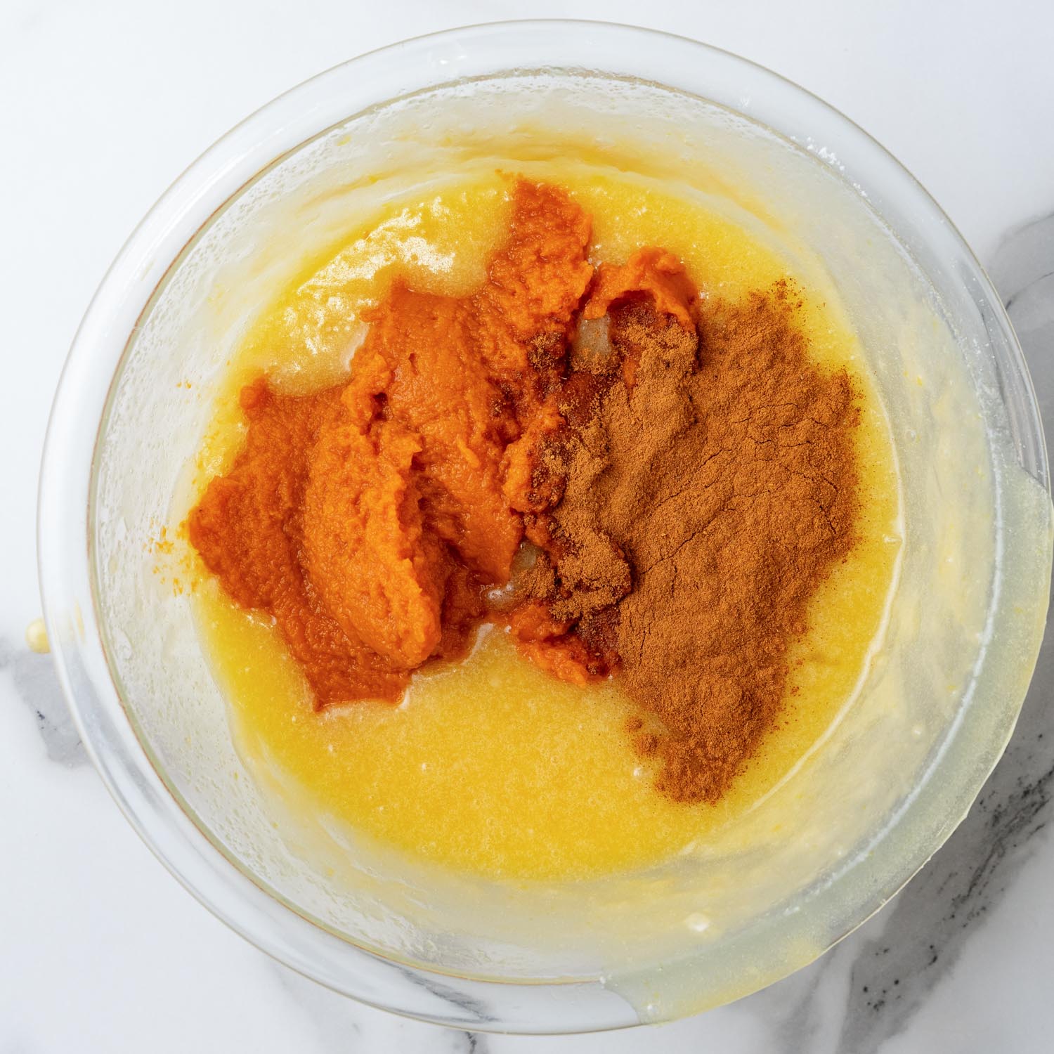 pumpkin puree and spices added to a bowl of whisked butter, sugar, and eggs.