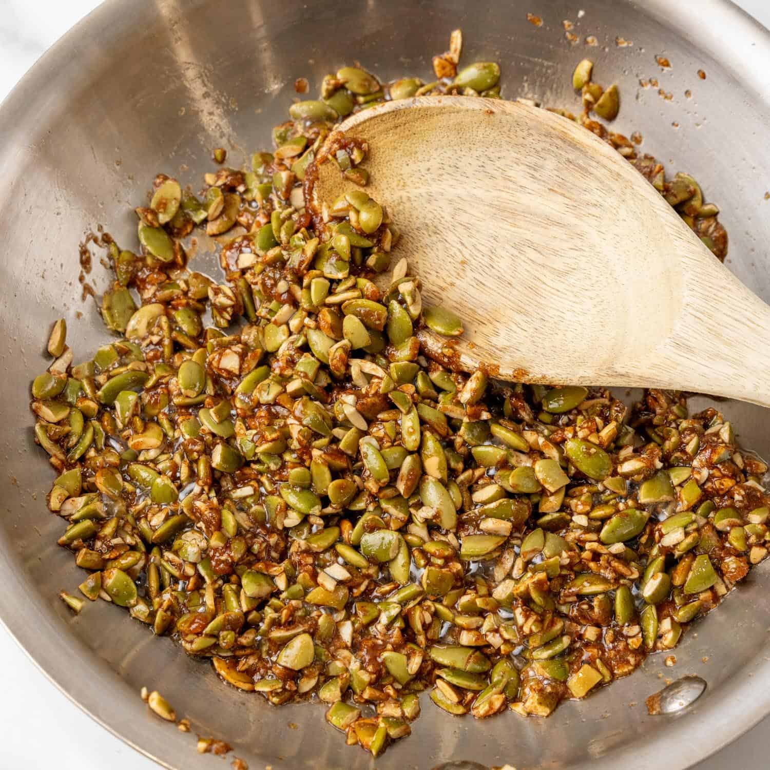 praline pumpkin seed mixture cooking in a small skillet.