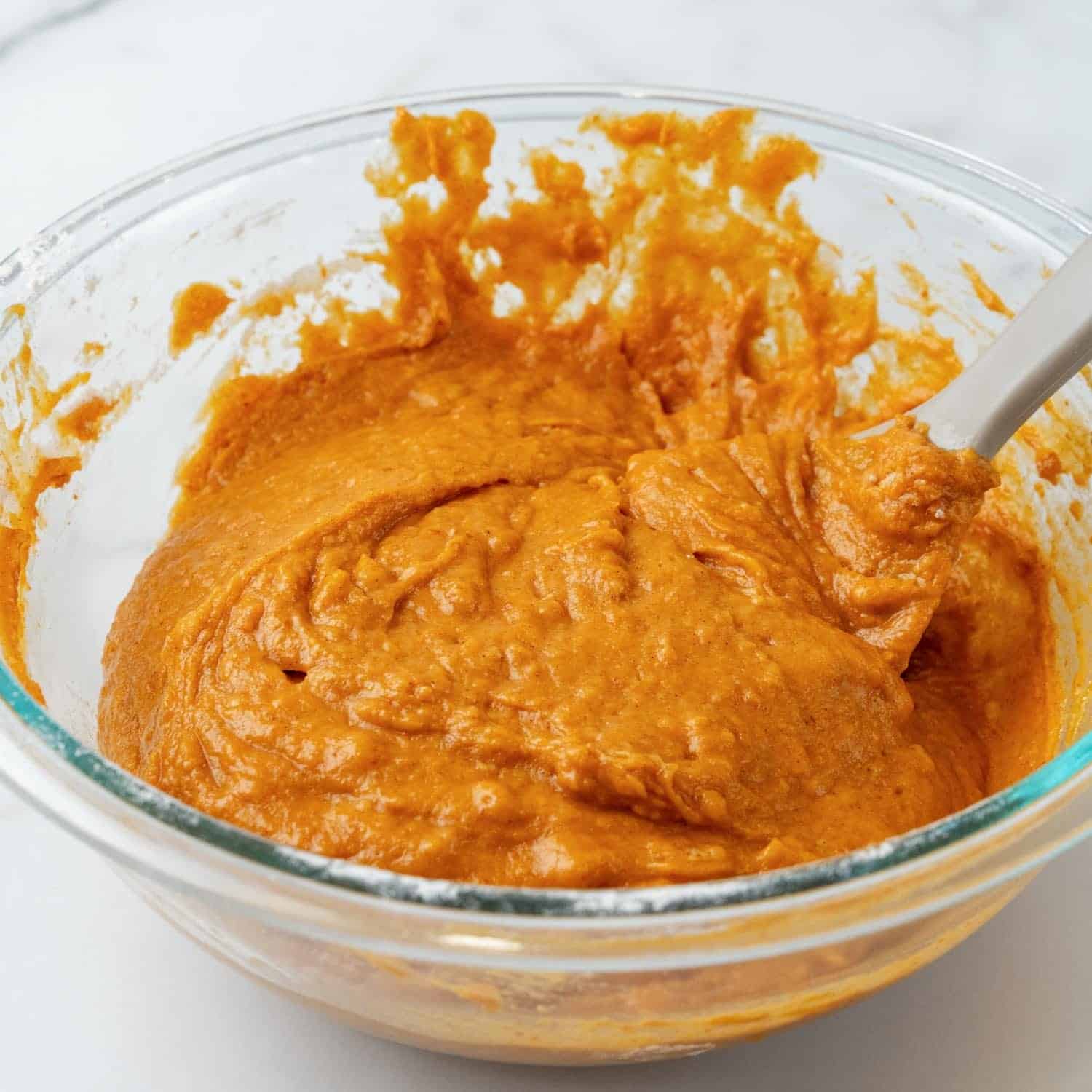 pumpkin muffin batter in a glass mixing bowl.