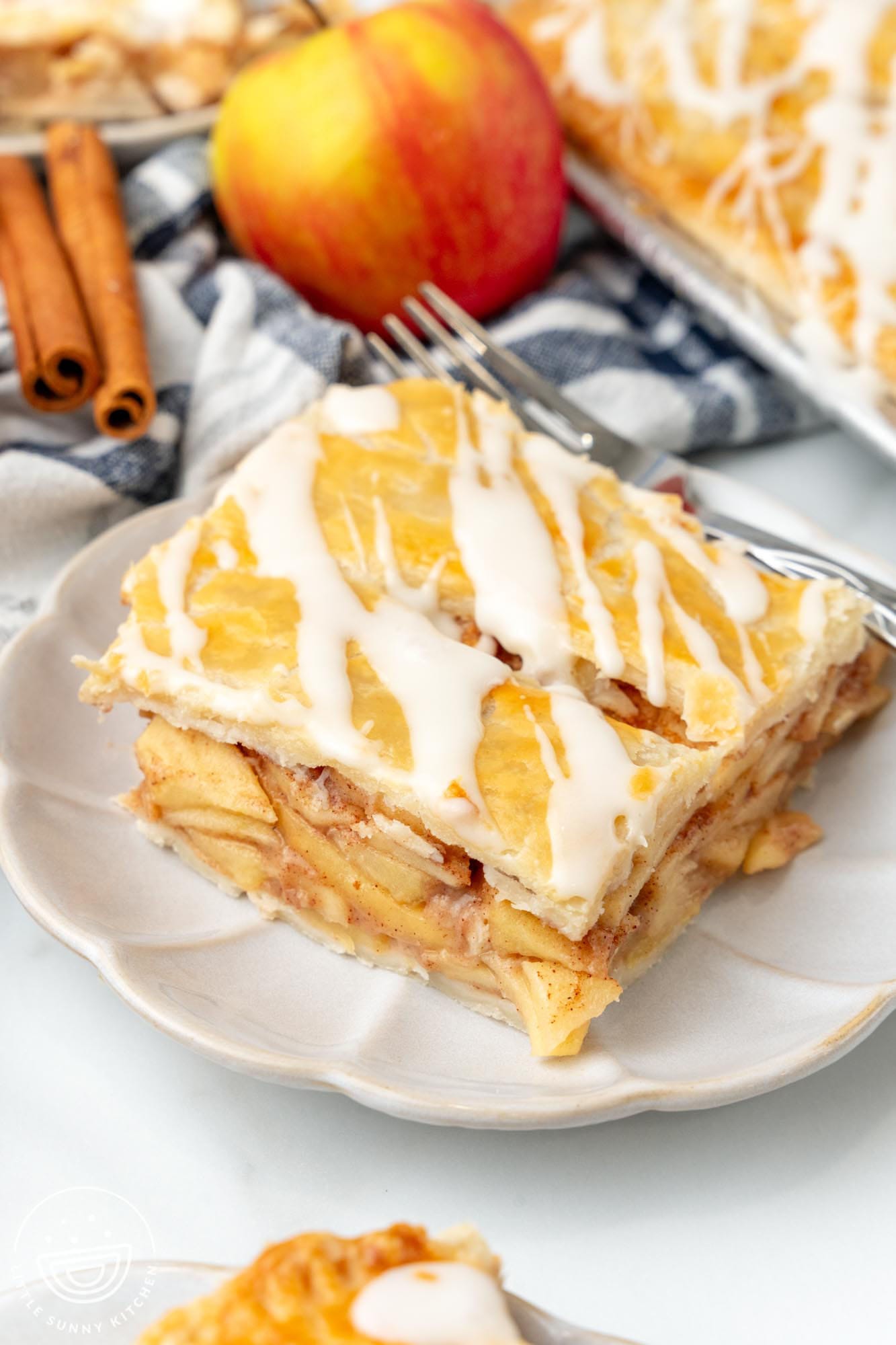 a piece of apple slab pie on a small white plate with a fork.