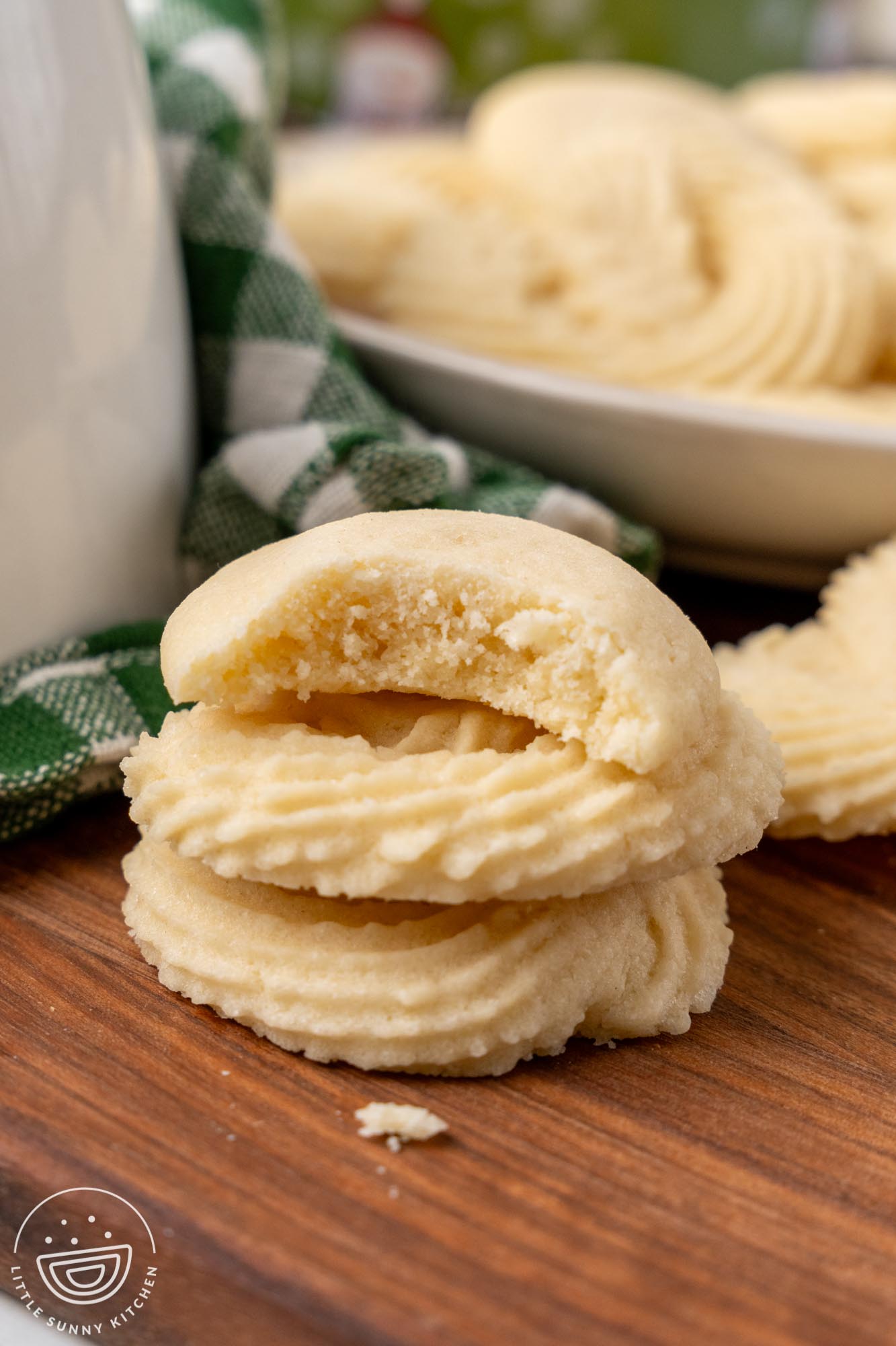 a stack of three danish butter cookies. One has a bite taken to show the tender, crisp texture.