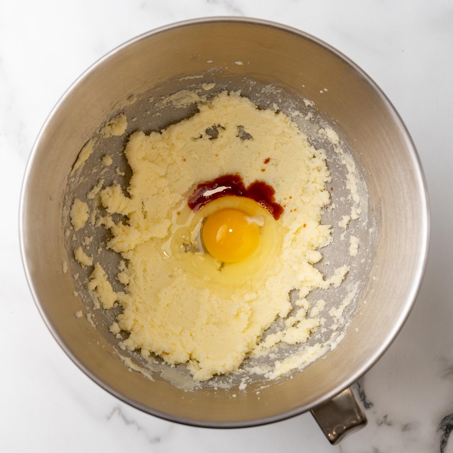 egg and vanilla added to creamed butter and sugar in a bowl.