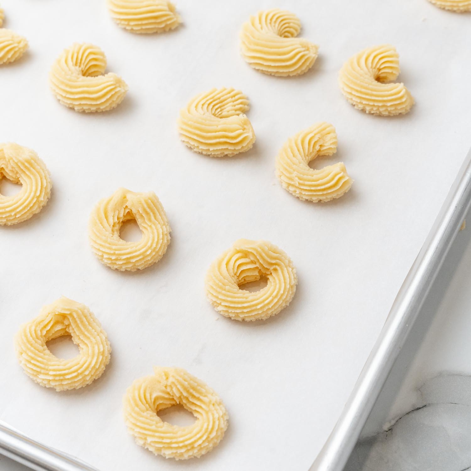 danish butter cookie dough piped into ridged circle shapes on parchment paper.