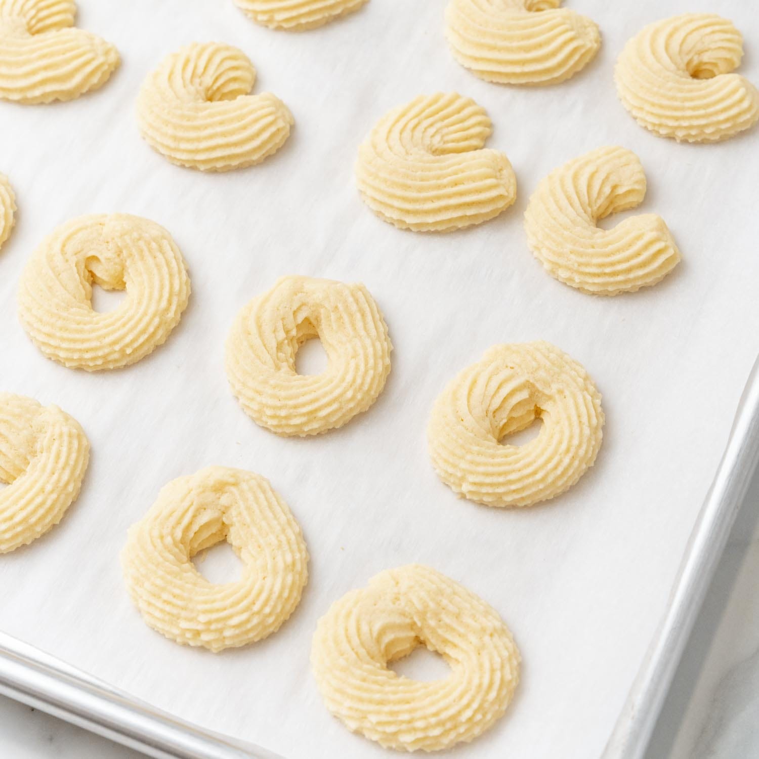 homemade danish butter cookies baked on a parchment lined baking sheet.