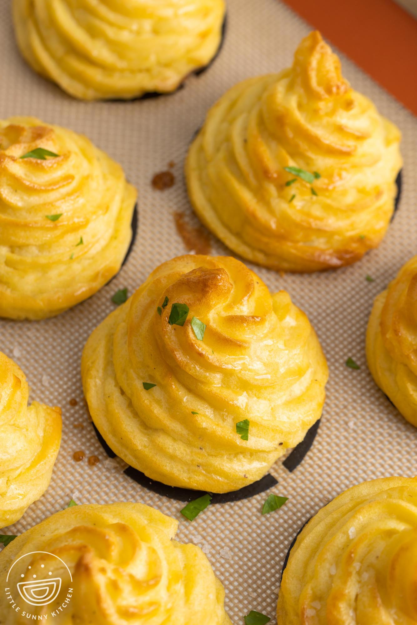 closeup of browned duchess potatoes on a silpat cookie mat. 