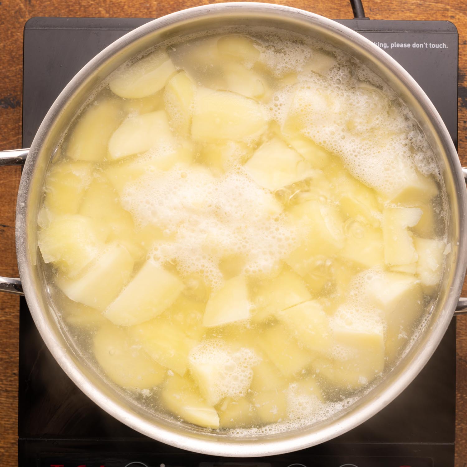 diced potatoes boiling in a metal pot.