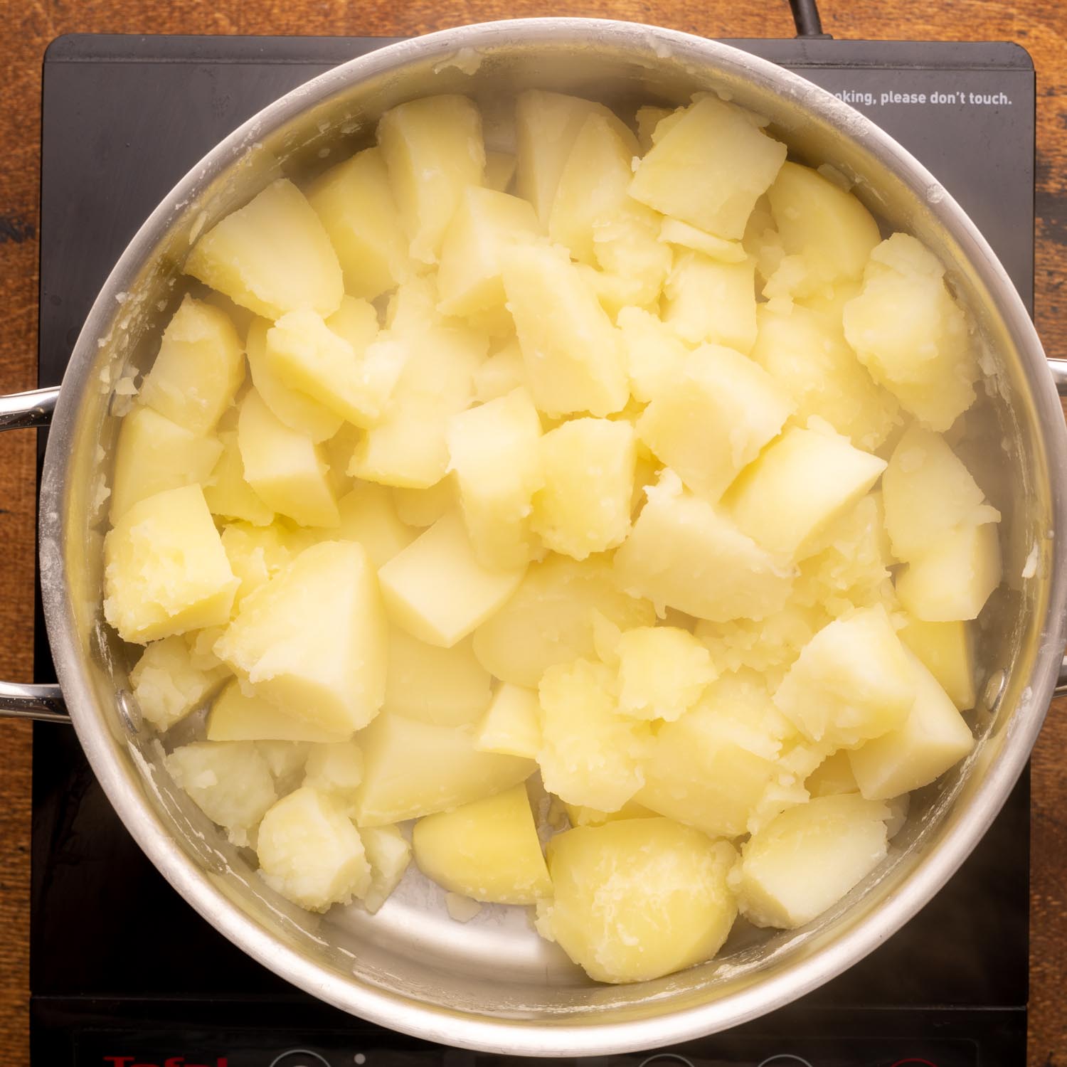 boiled potatoes in a pot with the water drained away, ready for mashing.