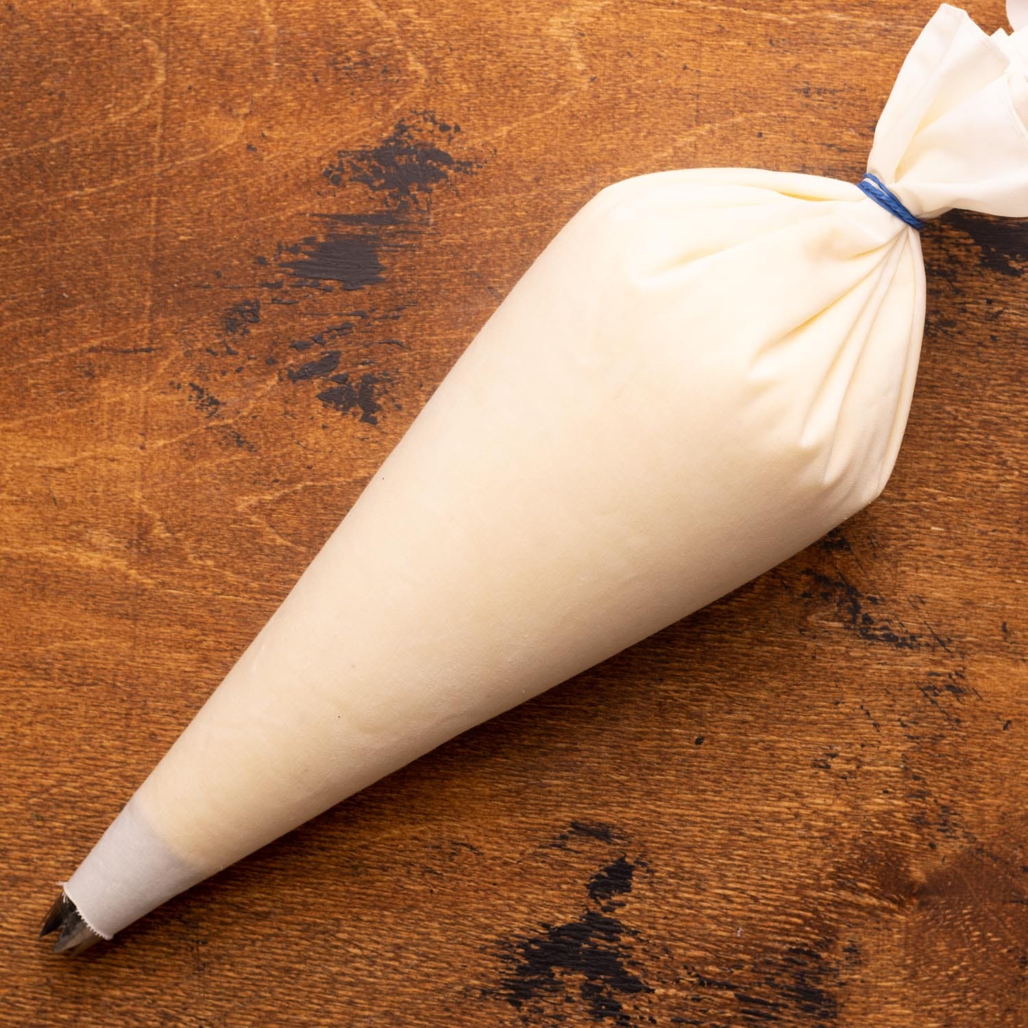 mashed potatoes in a large piping bag with a star tip, on a wooden surface.