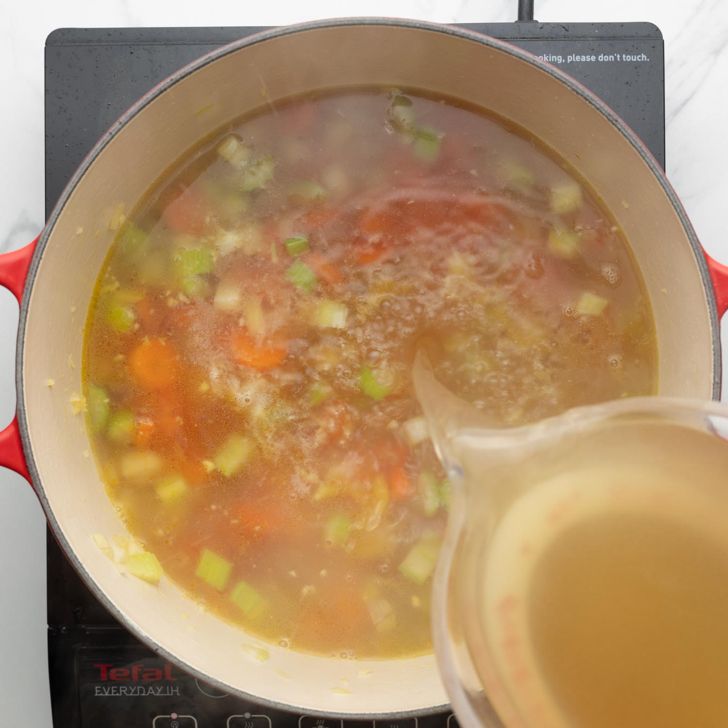 chicken stock poured into a soup pot.