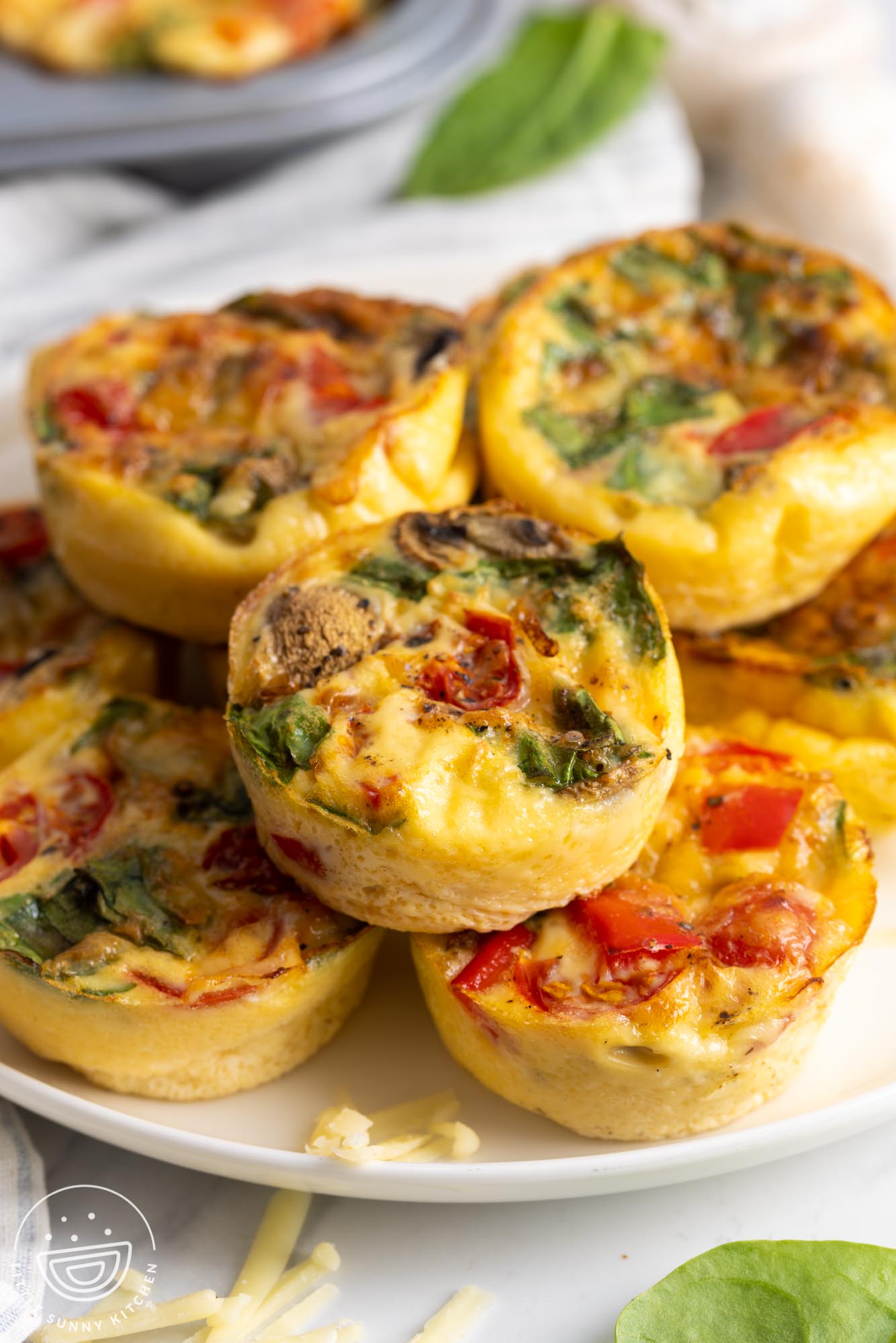 baked egg muffins stacked on a white plate.