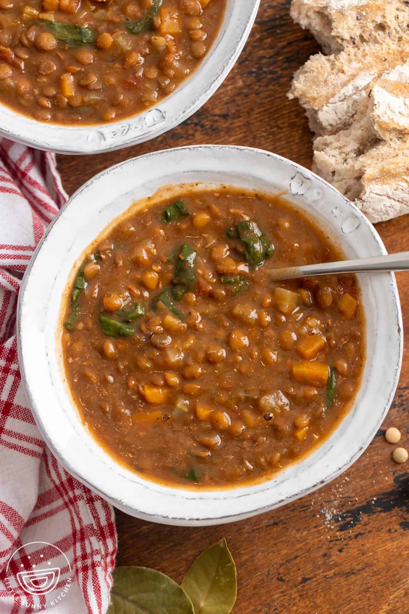 overhead view of a white rustic ceramic bowl filled with thick lentil soup.