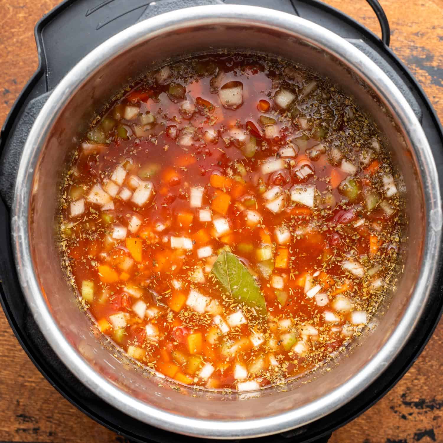 Broth added to lentil soup ingredients in an instant pot, viewed from above.