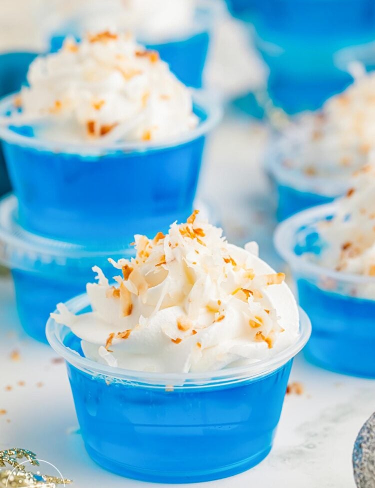 blue jack frost jello shots in plastic cups with whipped cream and coconut.