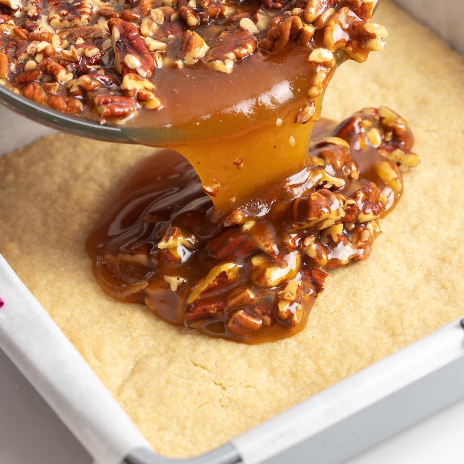 pecan mixture poured over partially baked crust to make pecan pie bars.