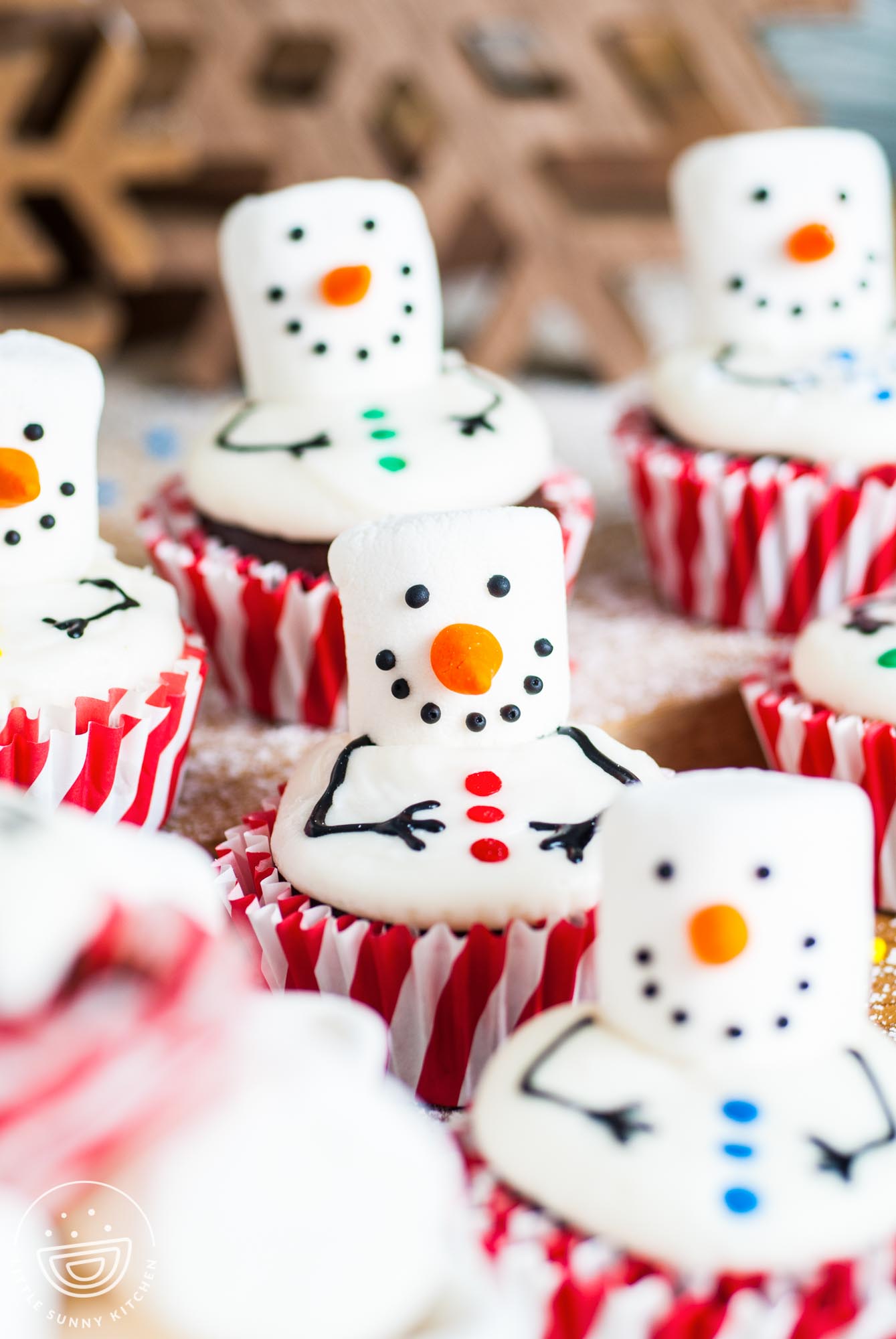 rows of snowman decorated cupcakes with red and white paper liners.