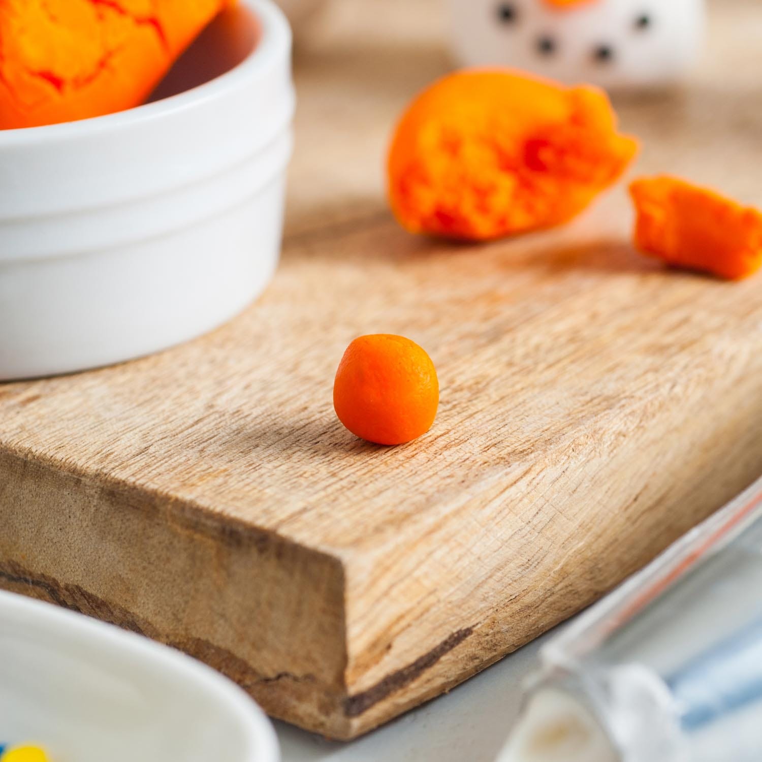 orange fondant rolled into a small bowl on a wooden cutting board.