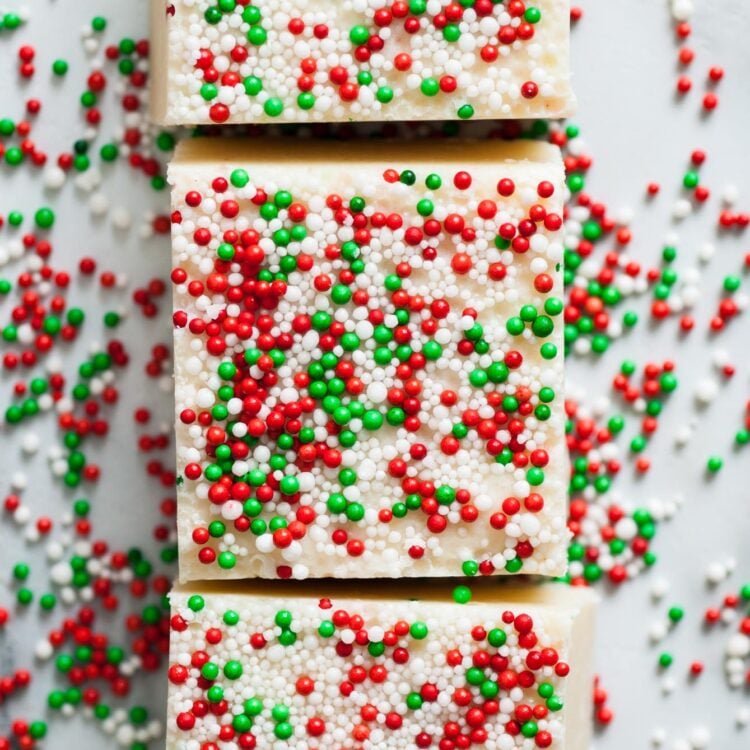 three square pieces of sugar cookie fudge topped with red white and green christmas nonpareils.