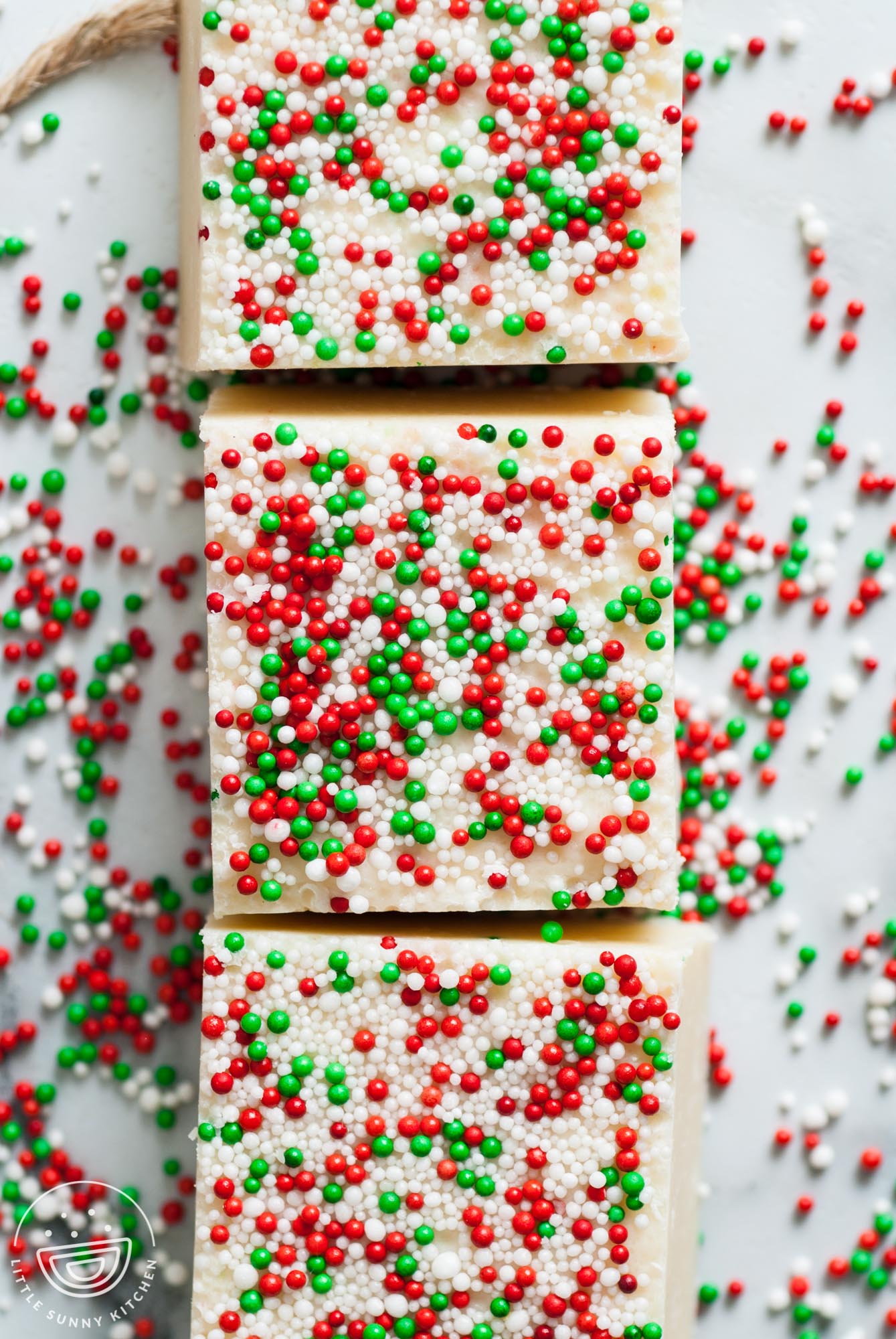 three square pieces of sugar cookie fudge topped with red white and green christmas nonpareils.