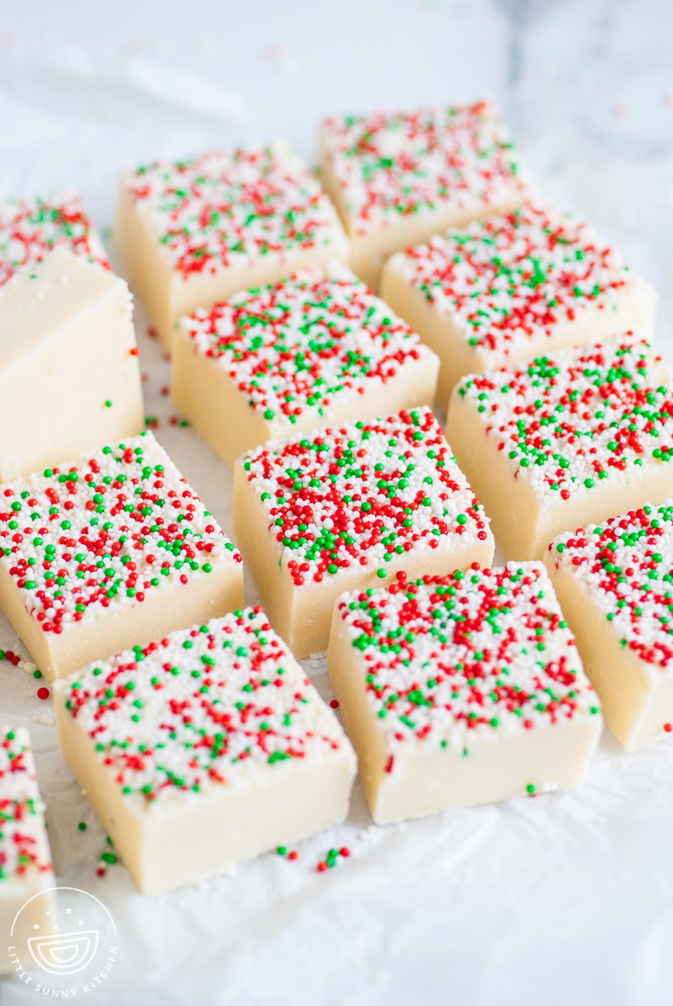 sugar cookie fudge squares with sprinkles, on parchment paper.