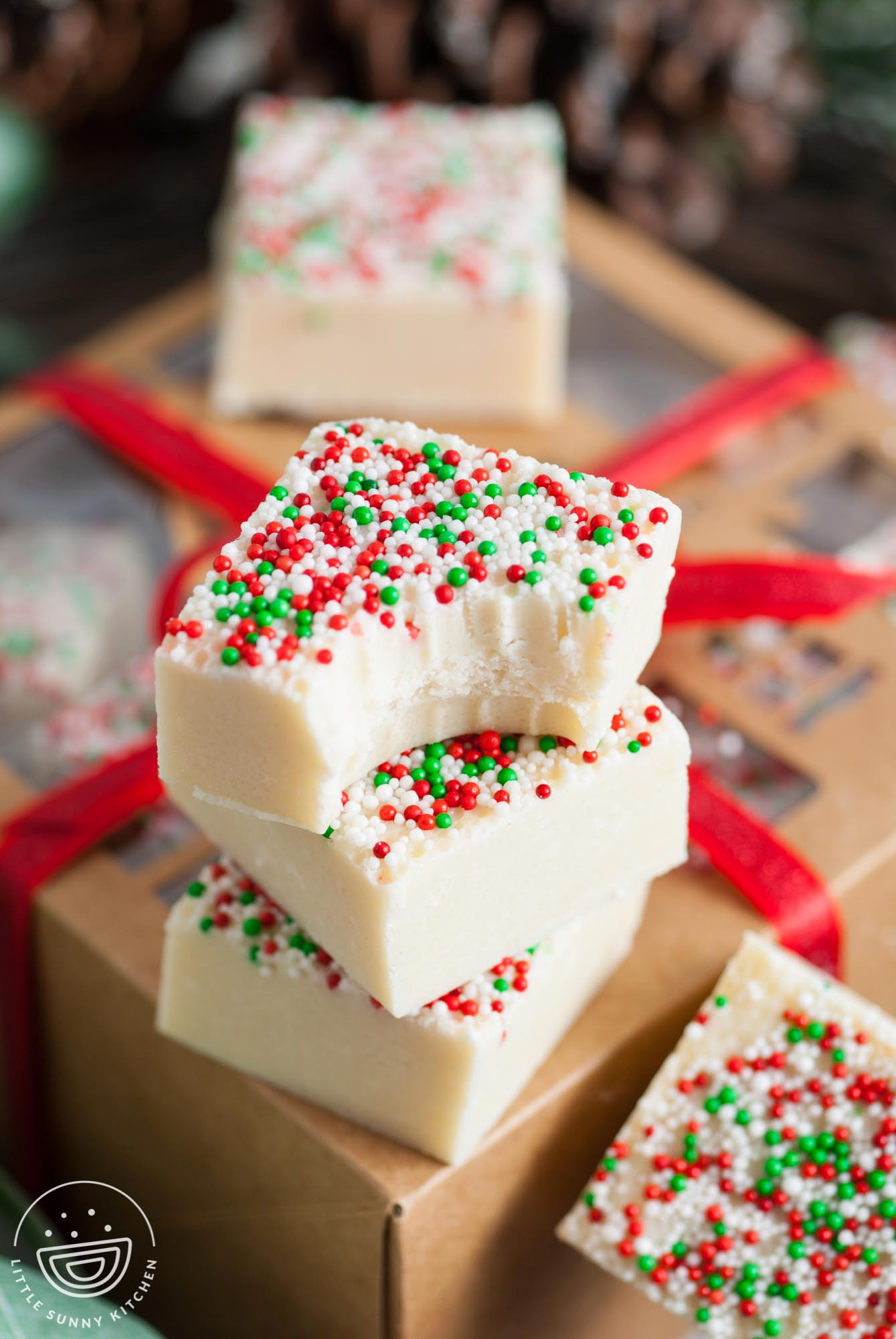 Three pieces of sugar cookie fudge on top of a brown kraft paper gift box.