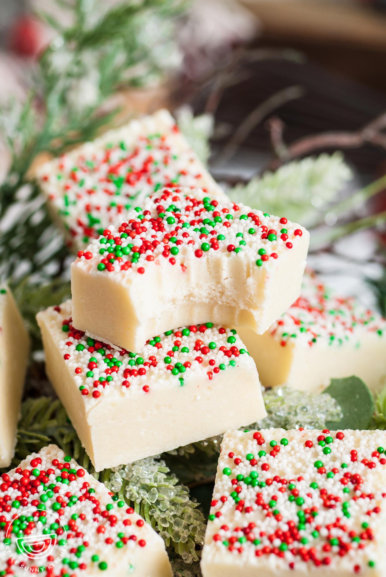 squares of sprinkled white fudge resting on top of holiday greenery.