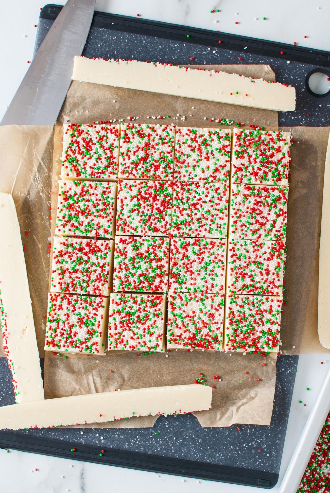 sugar cookie fudge cut into squares. The sides of the pan of fudge are trimmed away.