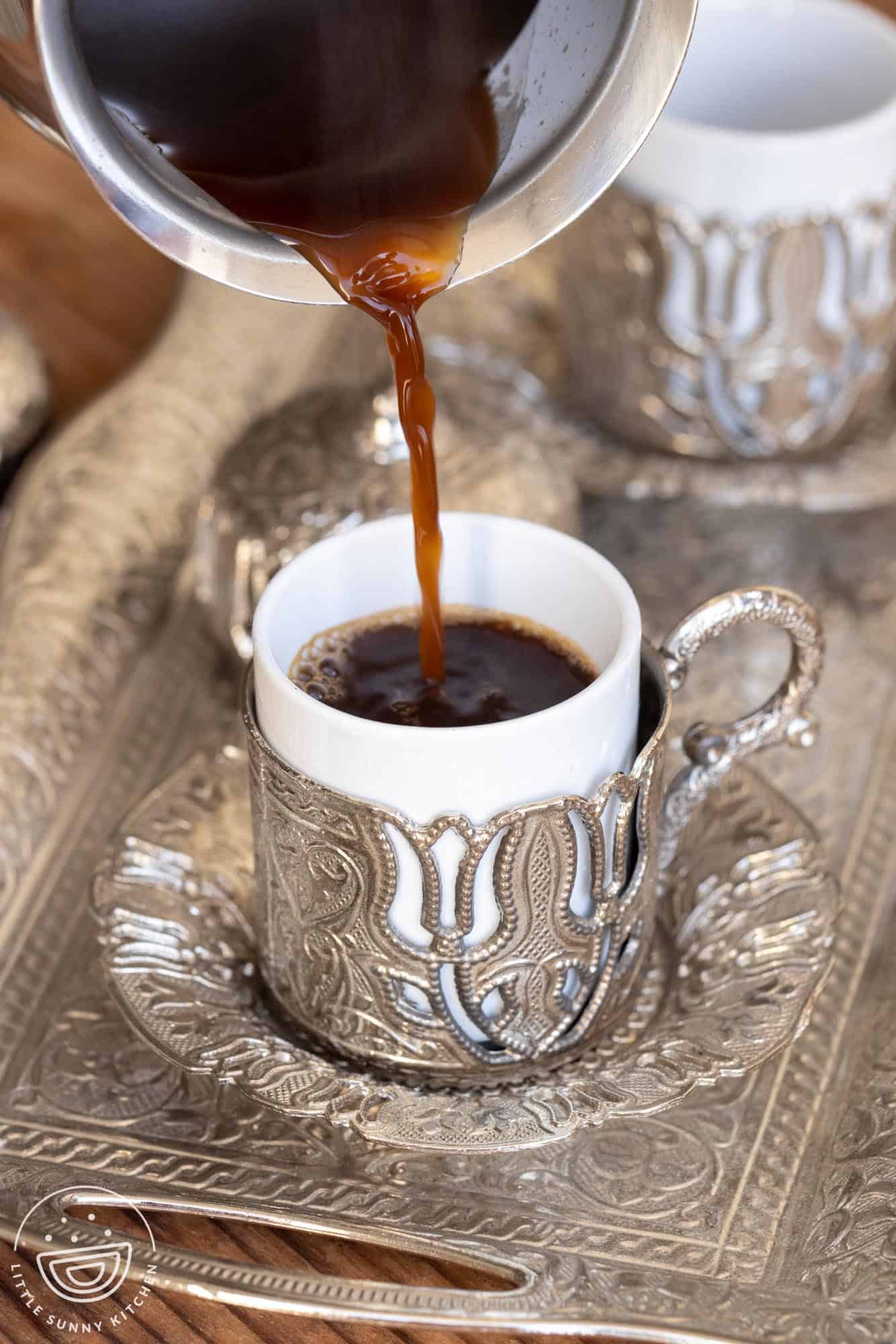 Pouring turkish coffee into a cup from an ibrik