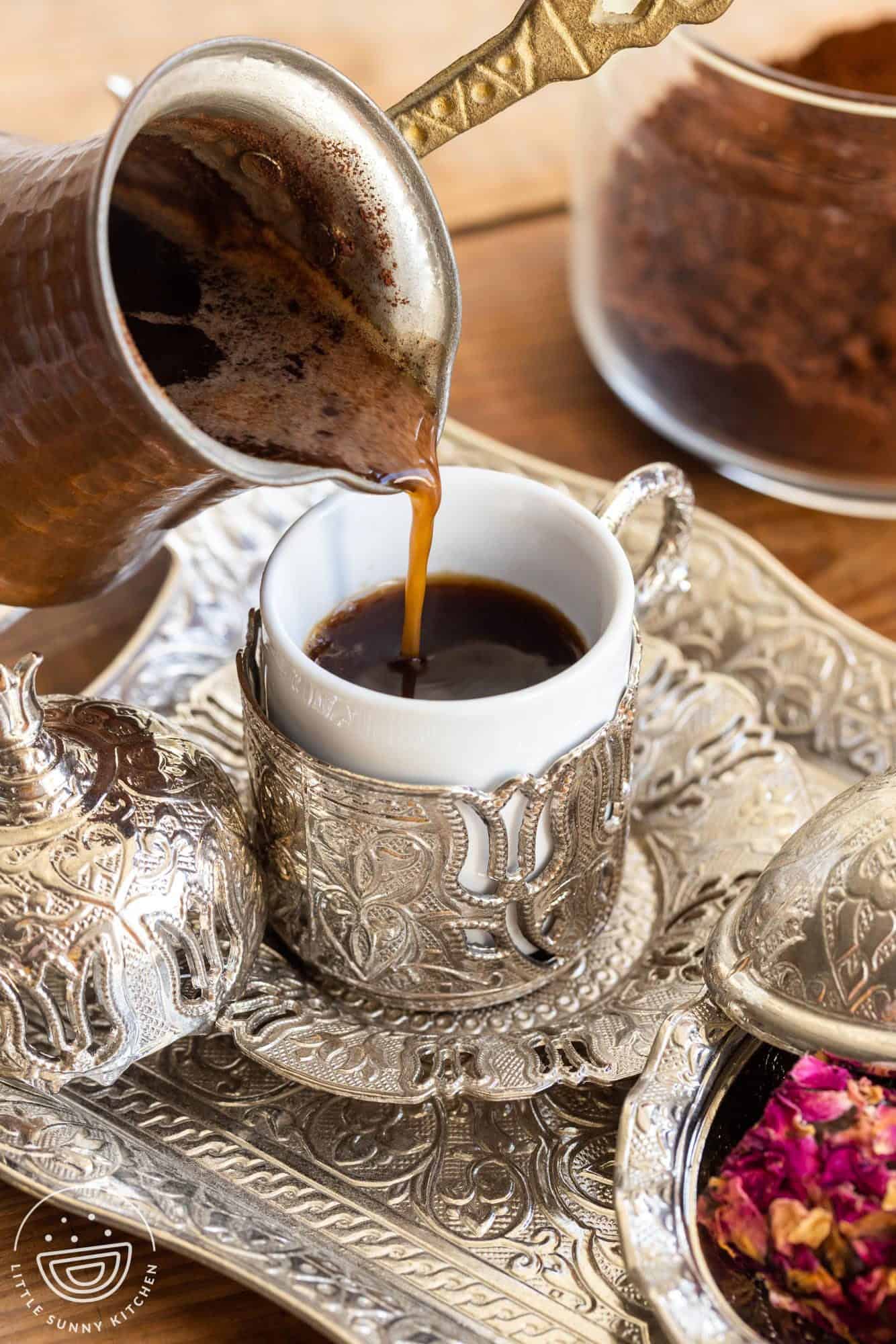 Pouring turkish coffee from a cezve into a demitasse cup