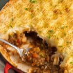 vegan shepherd's pie with textured criss cross mashed potato topping, served with a metal spoon.
