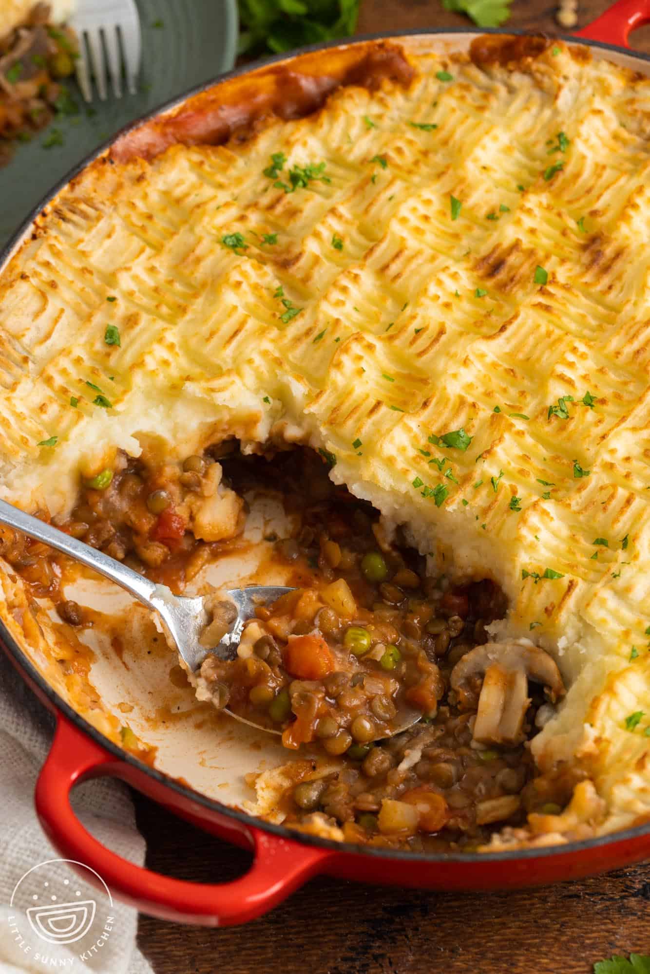 vegan shepherd's pie with textured criss cross mashed potato topping, served with a metal spoon.