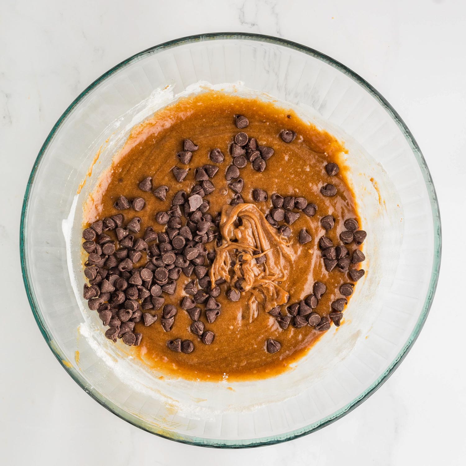 chocolate chips added to a glass bowl of brown butter blondie batter.