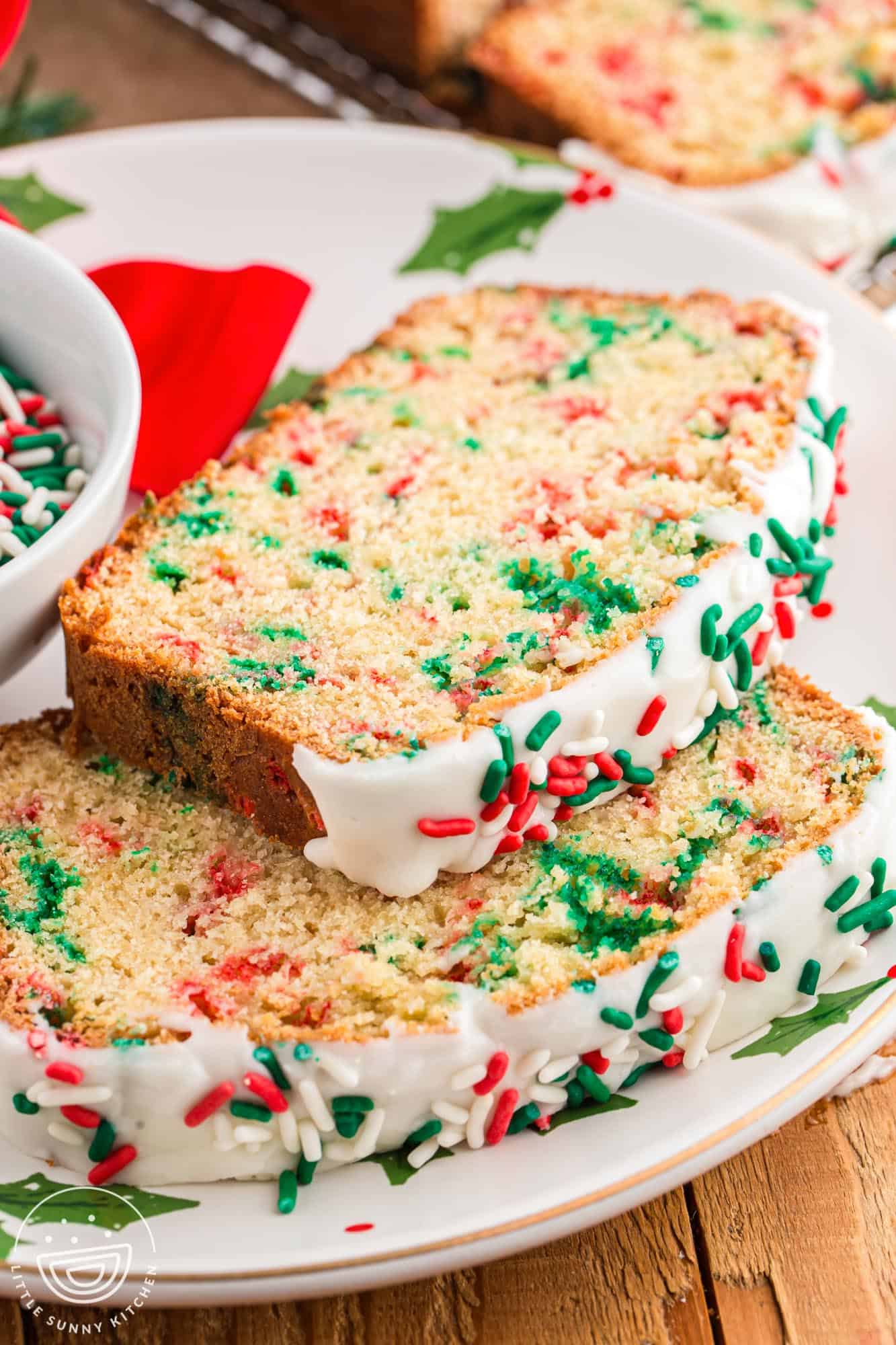Two slices of frosted christmas bread on a plate.
