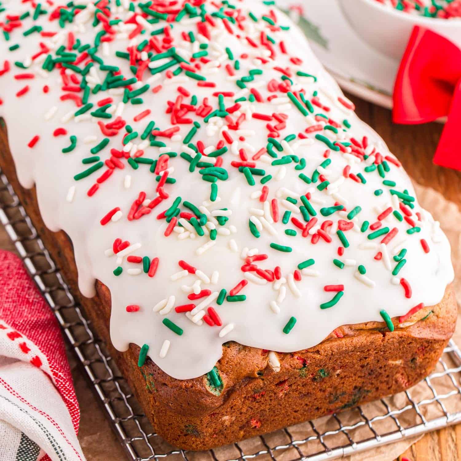 quick bread on a cooling rack, covered in thick white icing and holiday sprinkles.